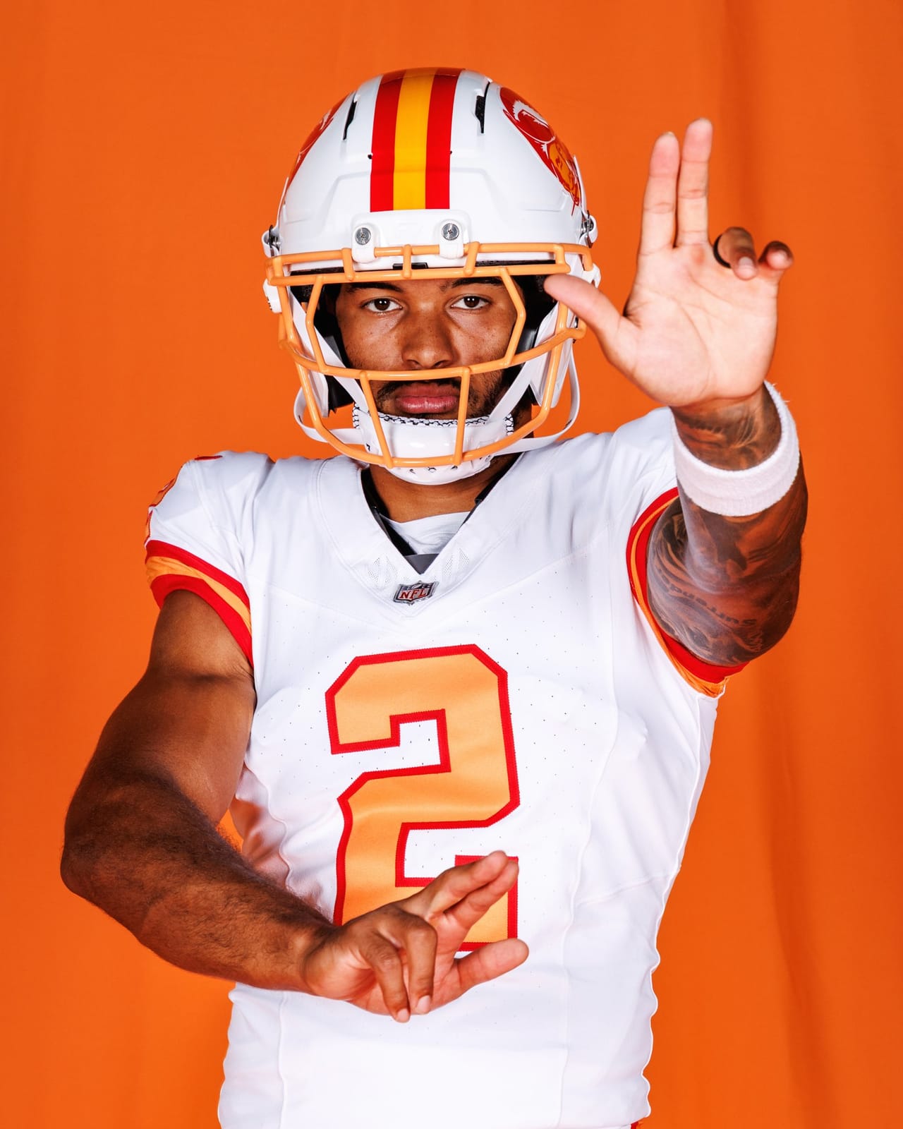 Tampa Bay Buccaneers creamsicle throwback uniform, white jersey with orange numbers outlined in red, white helmet with the Bucco Bruce logo and orange facemask