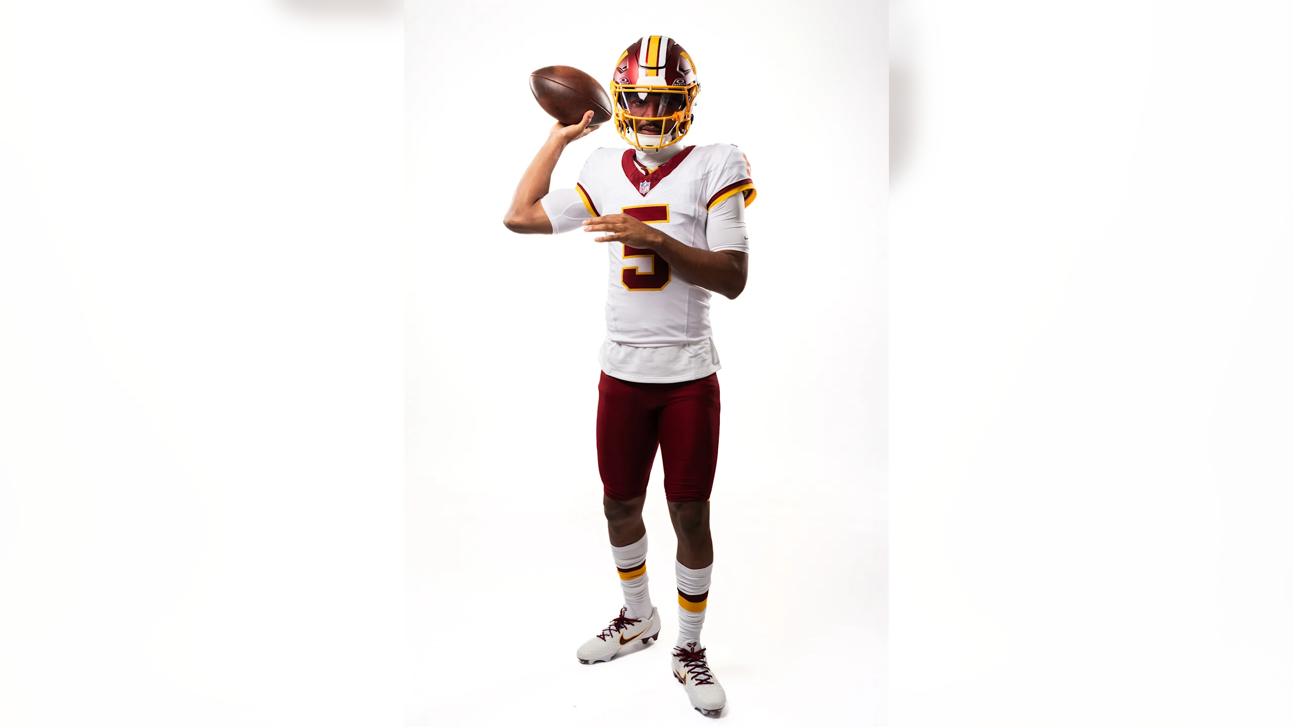 Jayden Daniels in full Washington Commanders throwback uniform throwing a football