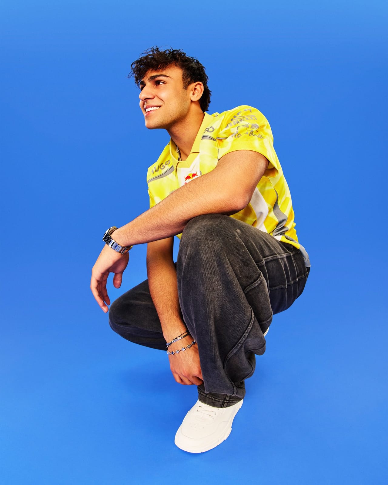 Visa Cash App RB F1 driver in a yellow Hugo team polo on a blue studio background ahead of the 2026 Miami Grand Prix Summer Edition livery reveal earlier in the race week