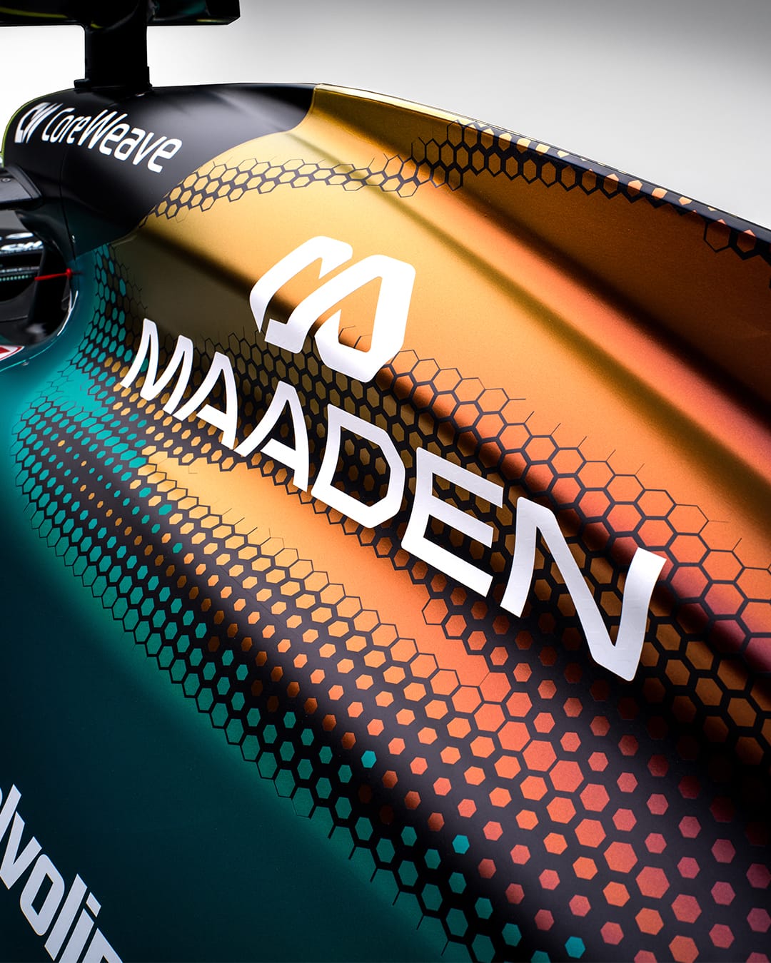 Aston Martin AMR25 F1 Monaco Grand Prix 2026 Maaden iridescent livery close-up macro detail shot of the engine cover showing the green-to-gold hexagonal mesh gradient pattern at full resolution with the MAADEN wordmark in white set against the iridescent paint surface