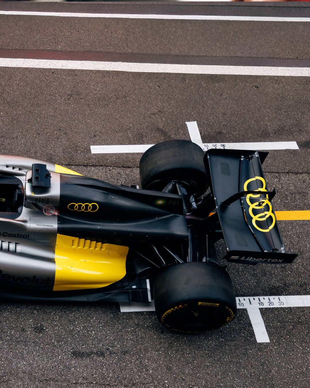 Audi F1 2026 Monaco Grand Prix special livery Tazio Nuvolari yellow tribute rear three-quarter view showing the bright yellow Audi rings on the chassis, yellow wheel arch trim, and yellow Audi rings on the rear wing endplates