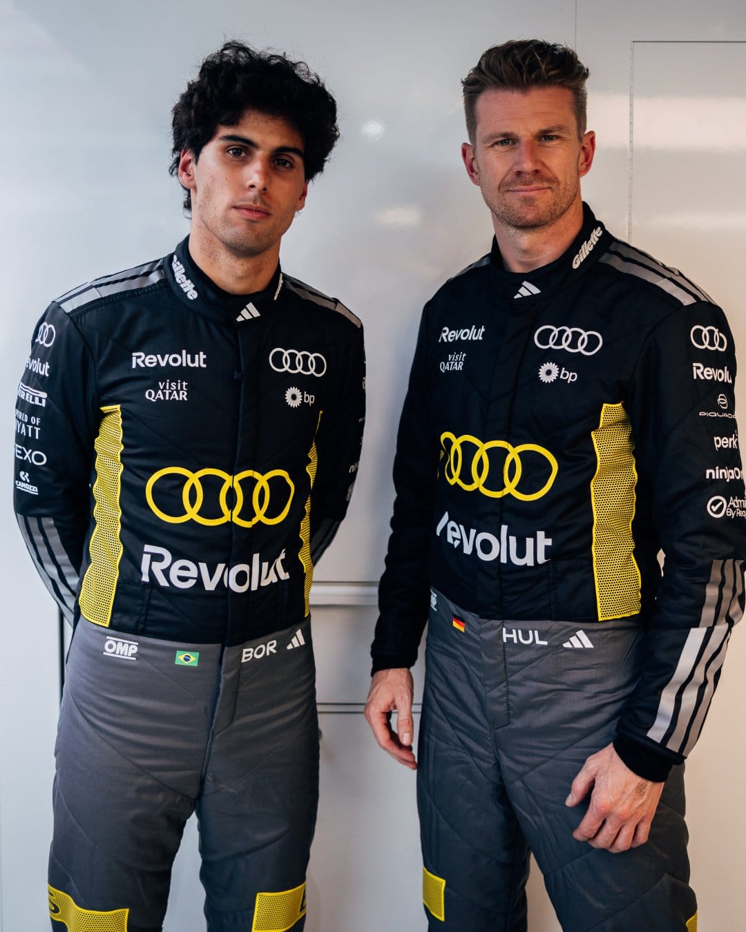 Audi F1 drivers Nico Hülkenberg and Gabriel Bortoleto in matching 2026 Monaco GP Tazio Nuvolari tribute race suits with black base, bright yellow Audi four-ring lock-up on the chest, and yellow accent stripes down the sides