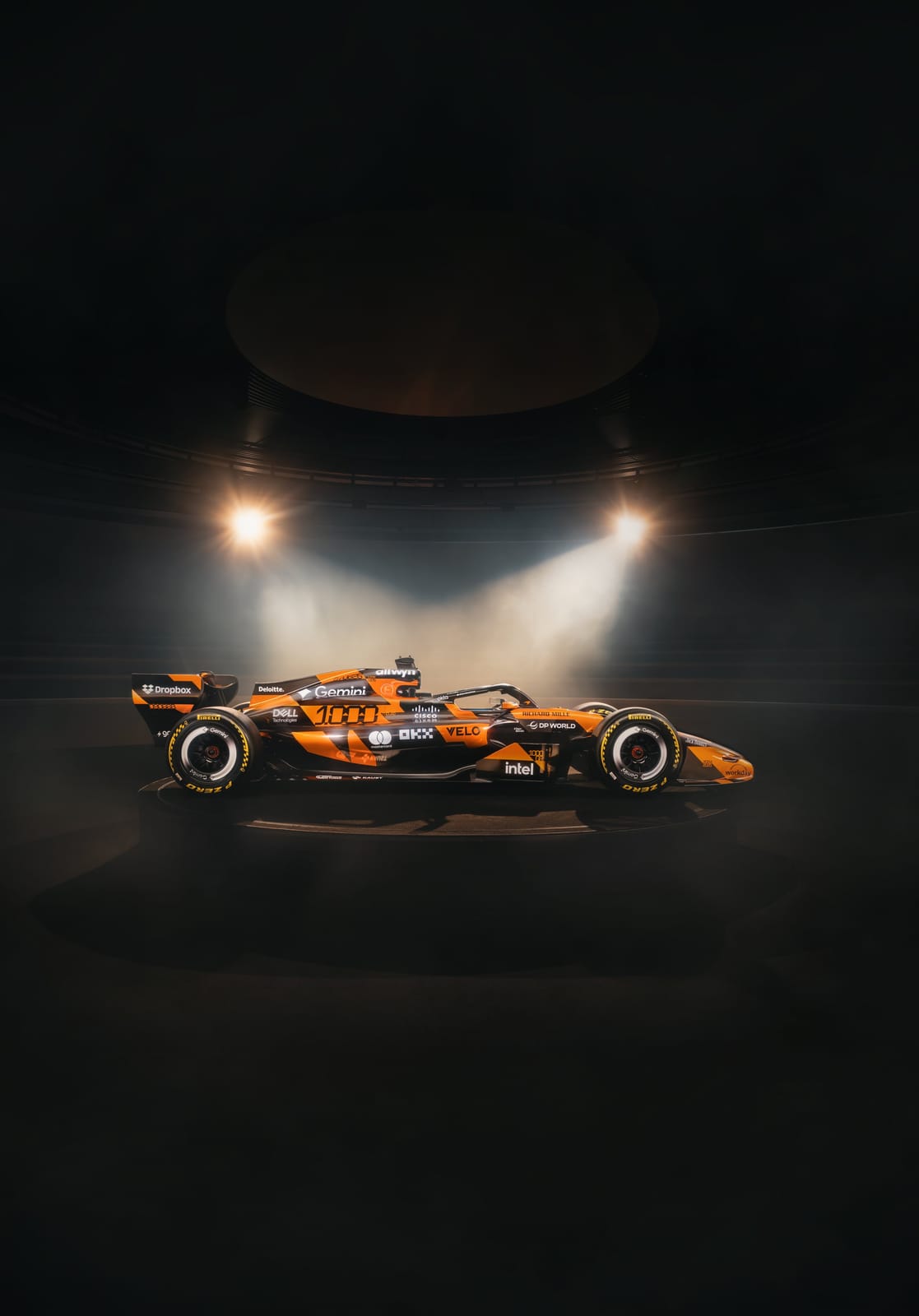 McLaren F1 Monaco Grand Prix 2026 special livery showing the engine cover and airbox detail with the orange and black retro treatment in front of the fragmented McLaren typography wall installation
