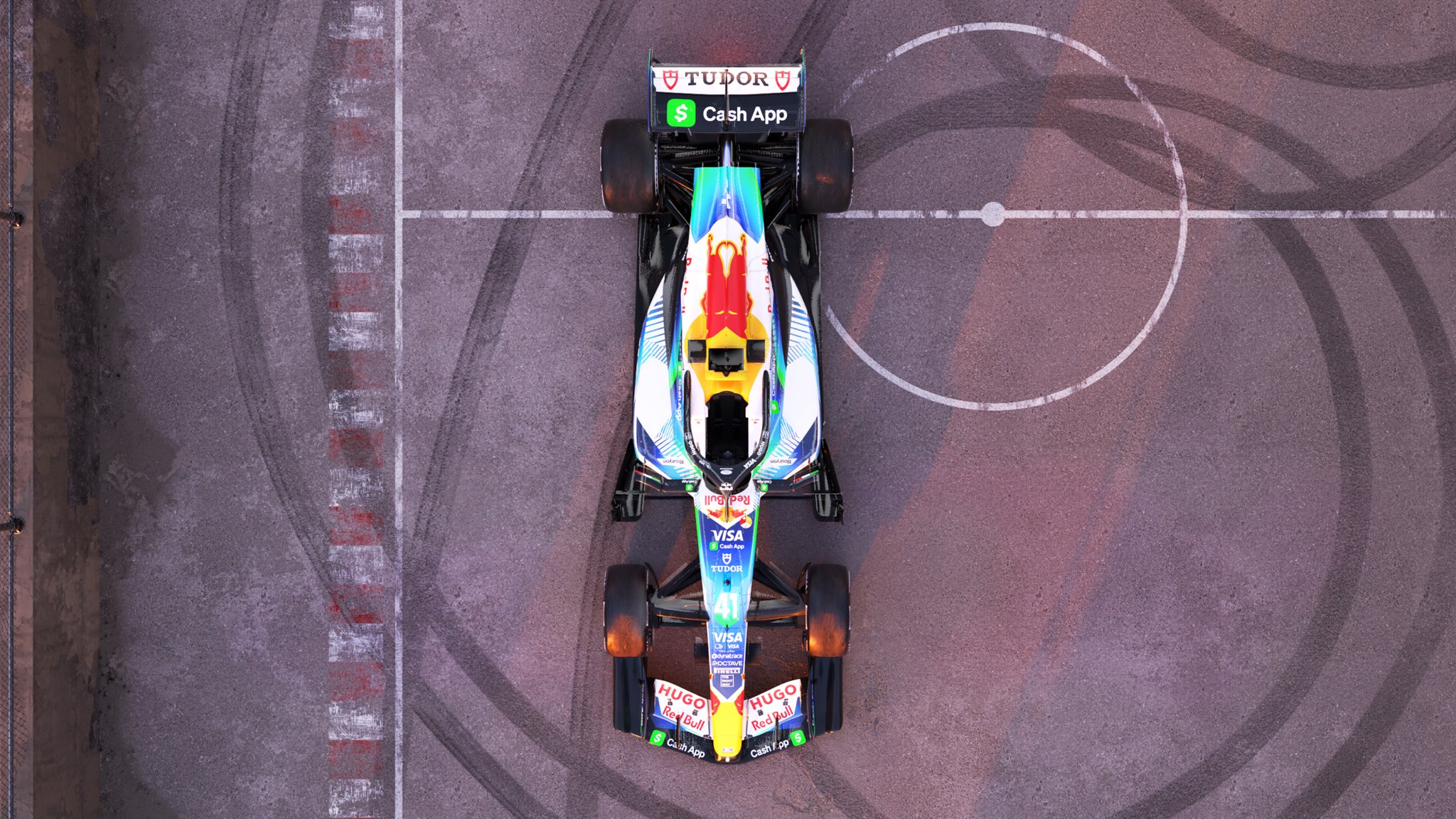 Visa Cash App Racing Bulls F1 Barcelona Grand Prix 2026 soccer football livery overhead top-down view of the number 41 car parked inside the futsal court center circle with donut tire marks looped around it, showing the TUDOR and Cash App rear wing, the white upper bodywork with the Red Bull crest, and the navy floor edges from above