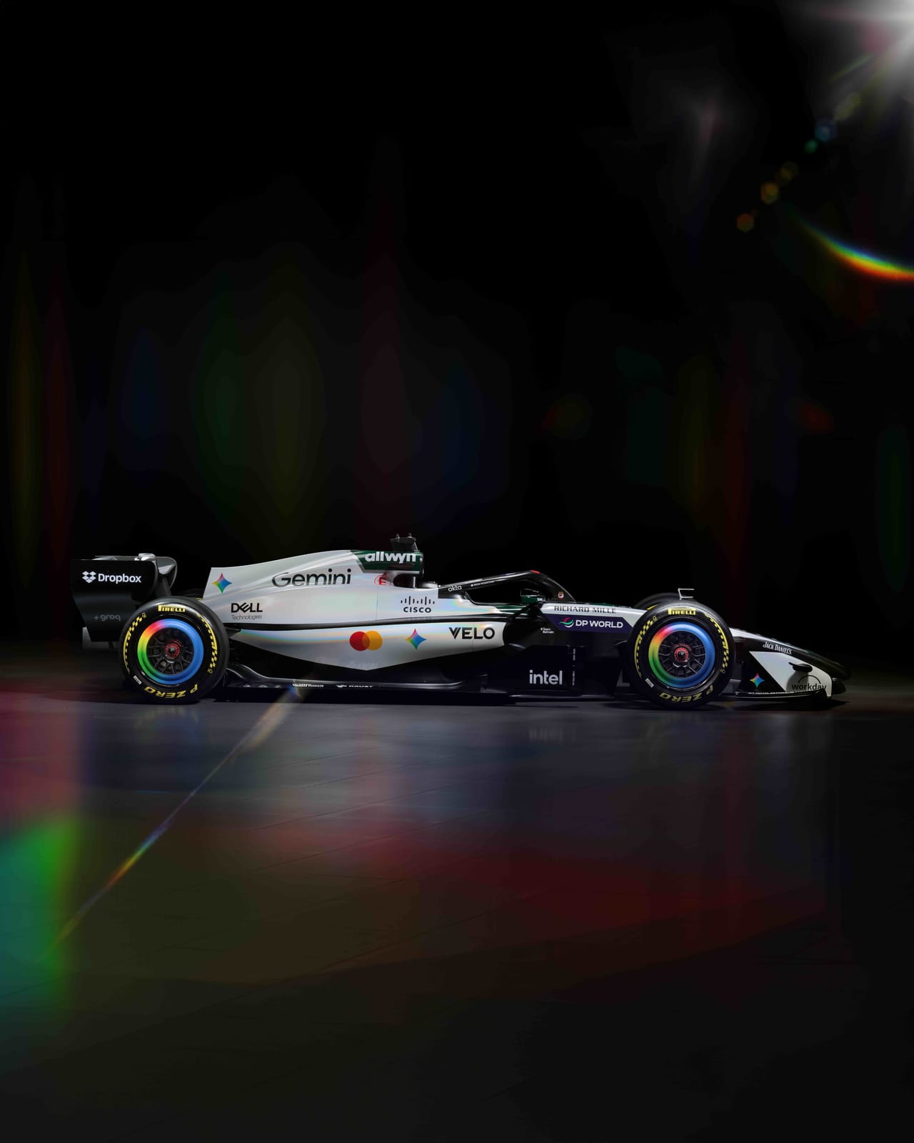 McLaren MCL40 2026 British Grand Prix heritage livery side view on a black studio backdrop highlighting the white-and-green color split, the Gemini four-color gem logo, and the rainbow-edged Pirelli wheel rims