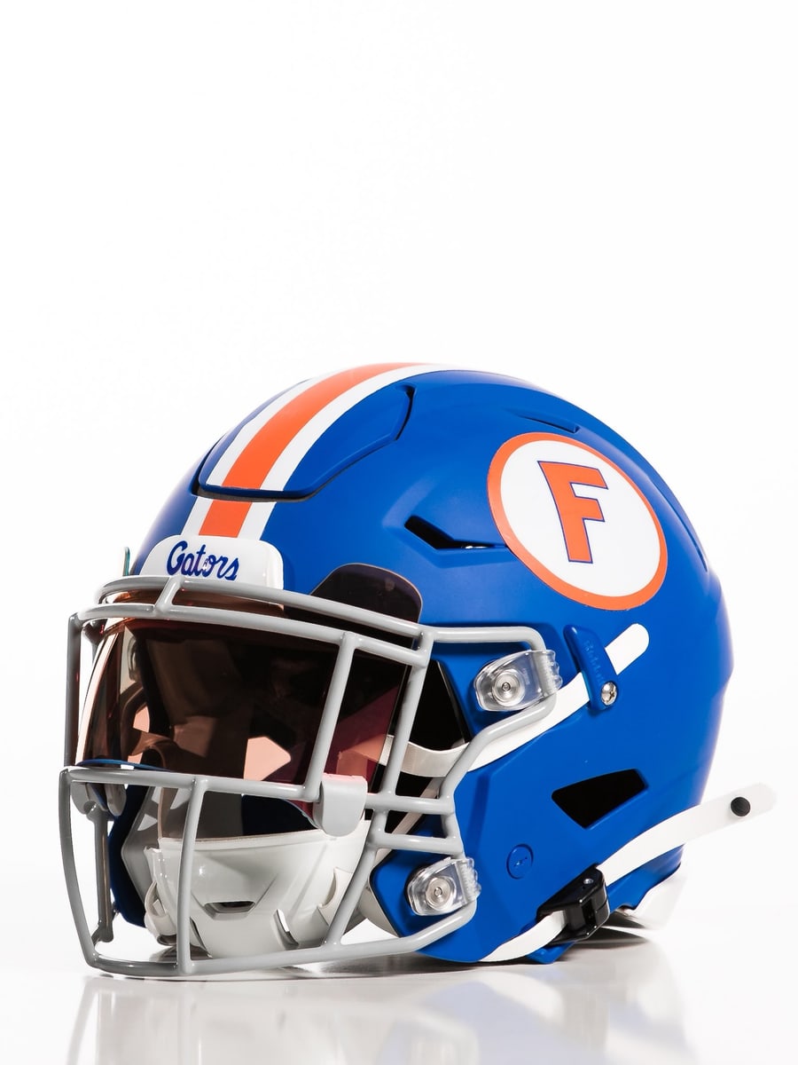 Close-up of the Florida Gators 2026 throwback helmet, royal blue shell with an orange and white center stripe, a white oval with an orange block F, and Gators script on the front bumper