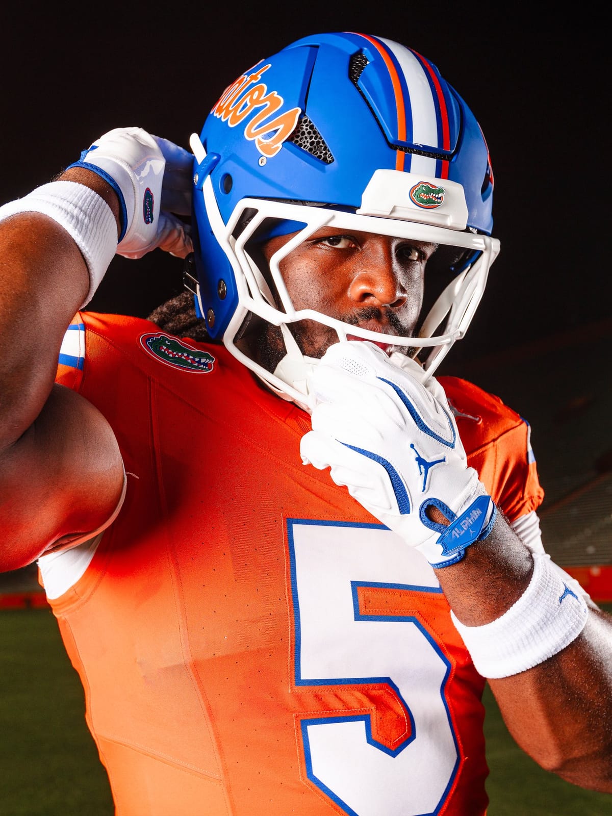 Florida Gators matte blue helmet worn with the orange jersey, showing the white facemask, the orange and white center stripe, and the white jersey number with a blue outline