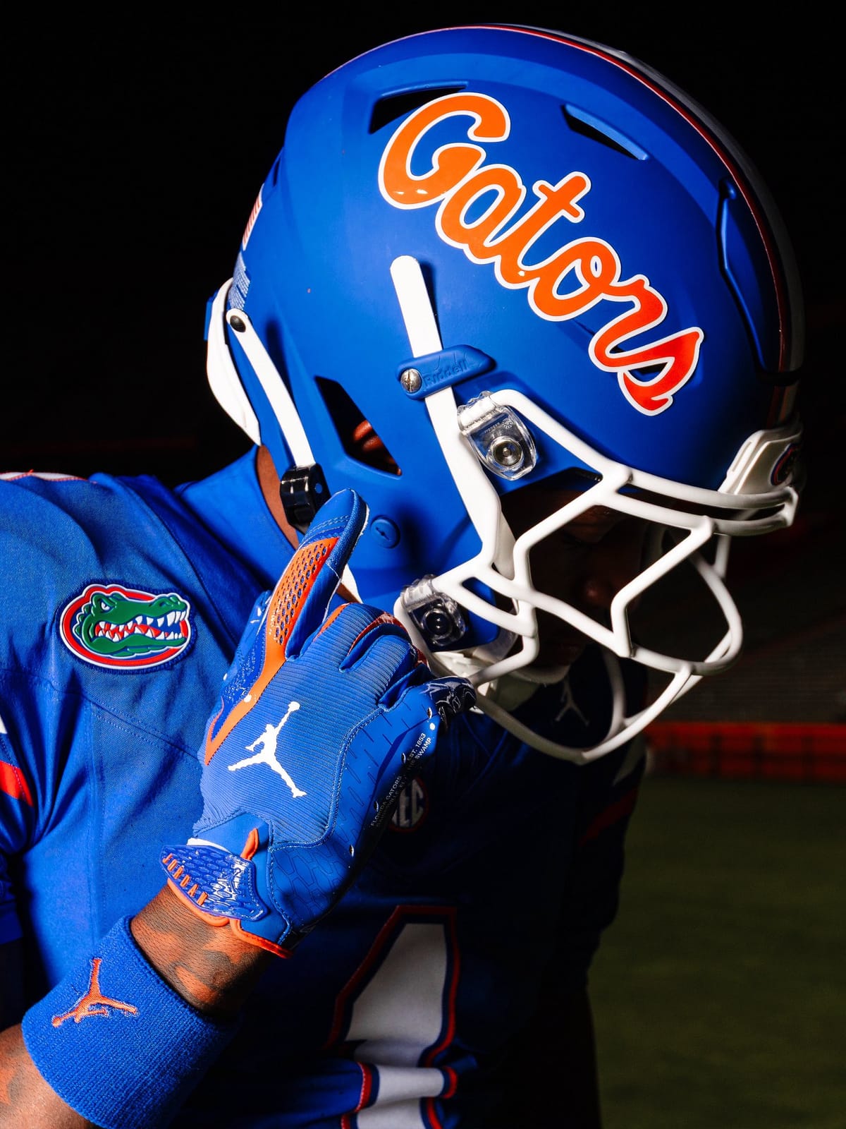 Close-up of the Florida Gators matte blue helmet showing the orange Gators script with a white outline, the white facemask, and the orange and white center striping