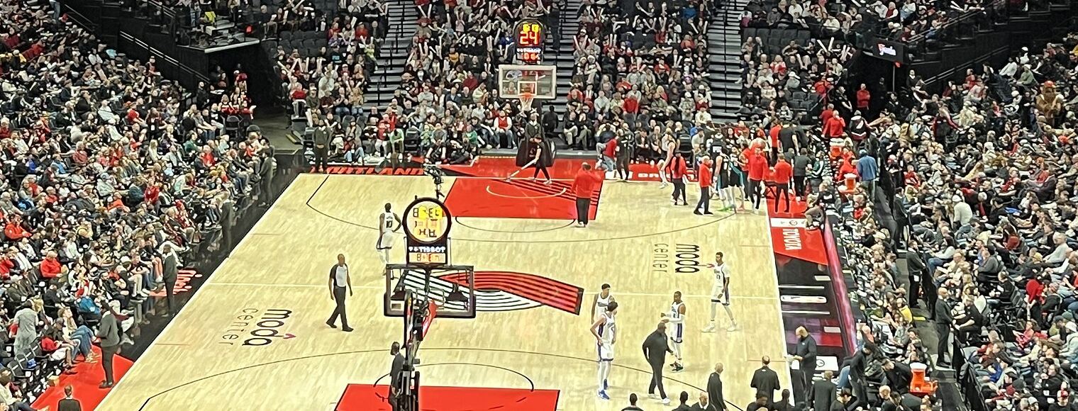 The Trail Blazers pinwheel logo, five red and five black stripes, painted on the court at the Moda Center during a game against the Kings in December 2025