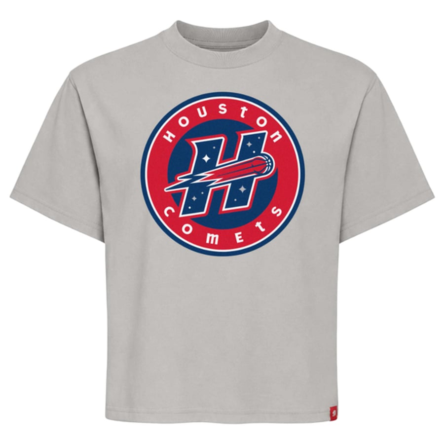 Houston Comets new round badge logo 2027 on a gray T-shirt: red ring with HOUSTON across the top and COMETS across the bottom in white, the slanted H with the comet in the navy center