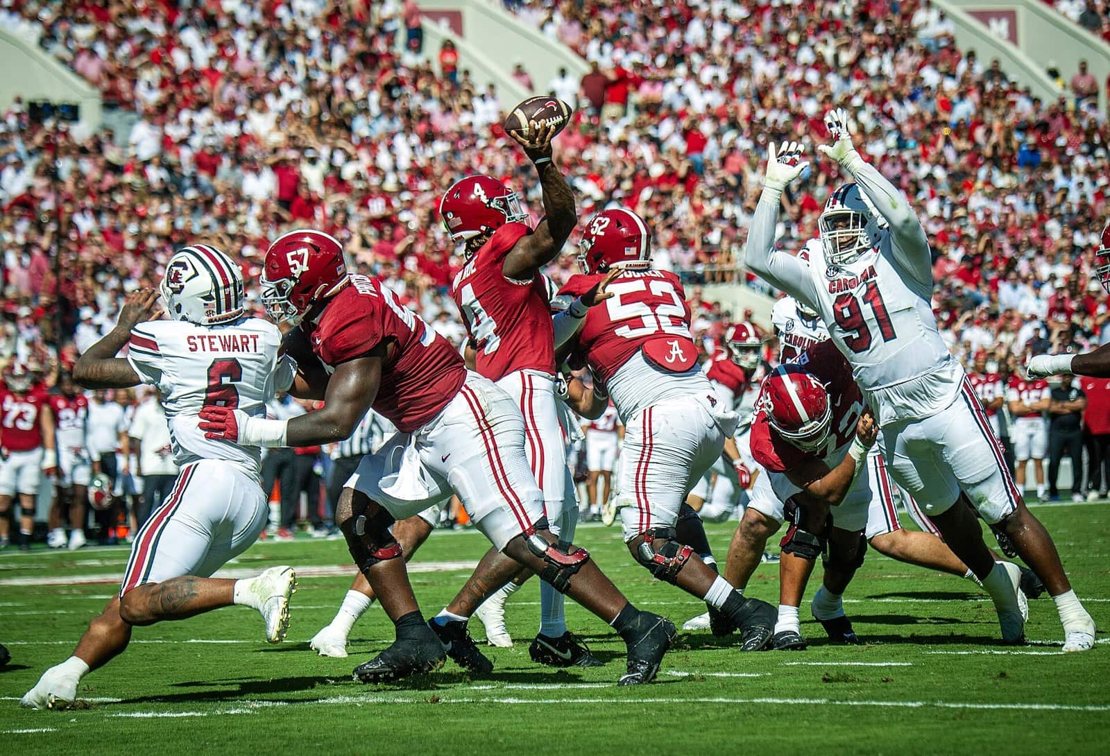 Alabama players in crimson home jerseys and white helmets at the line against South Carolina at Bryant-Denny Stadium