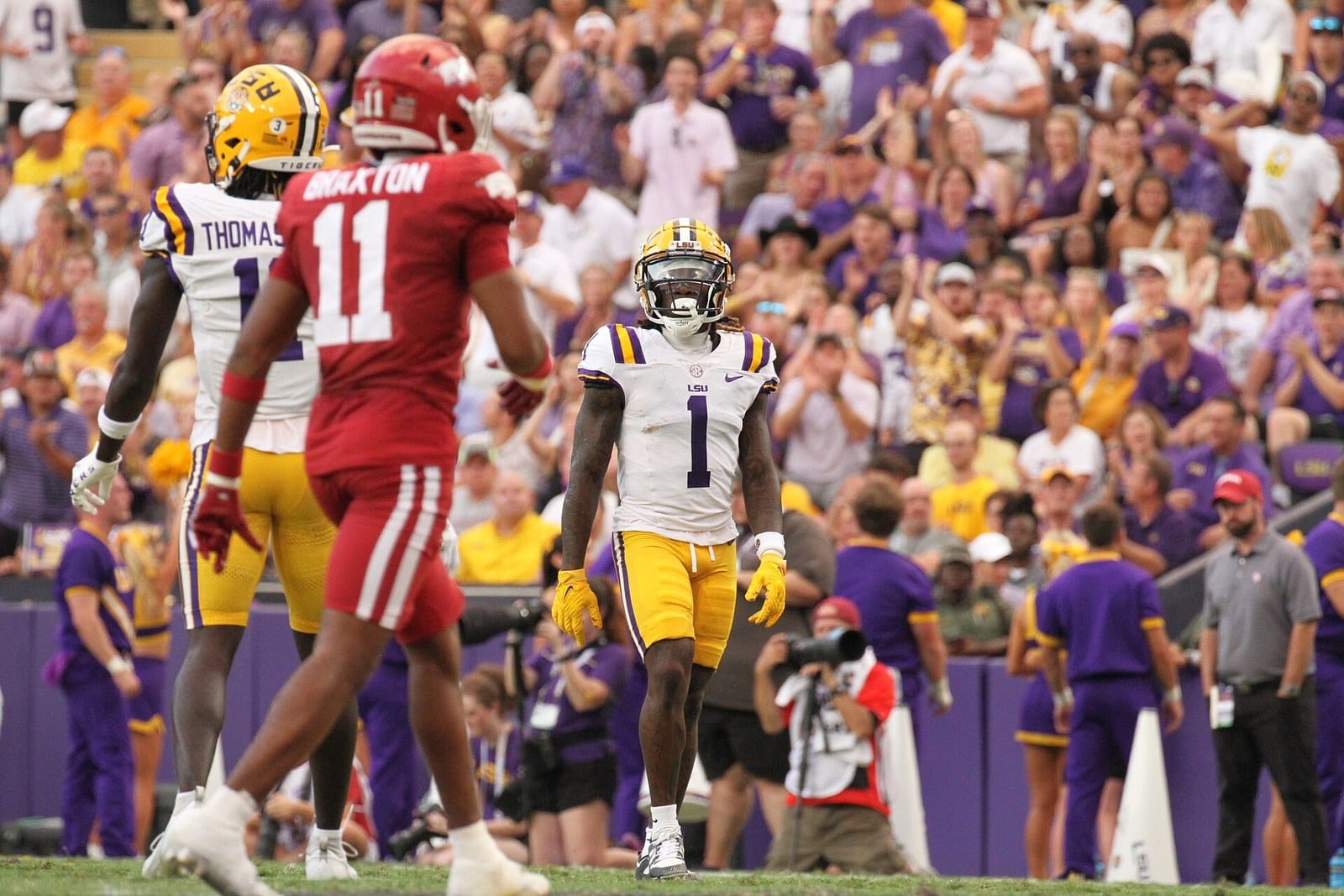 An Arkansas player in the red road jersey, red helmet and white pants among LSU players in white at Tiger Stadium