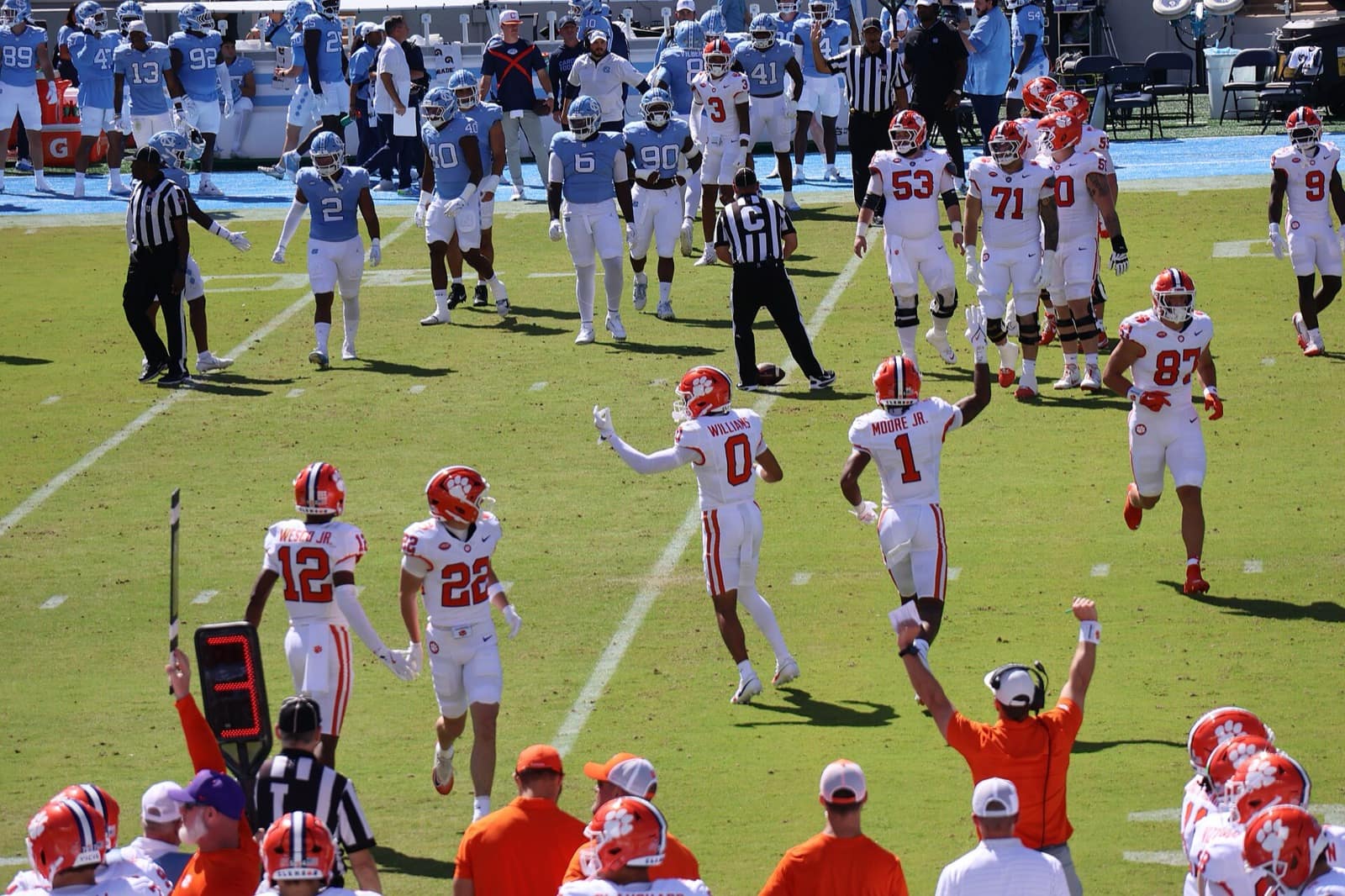 Clemson players in white road jerseys and orange helmets celebrate at Kenan Stadium in 2025