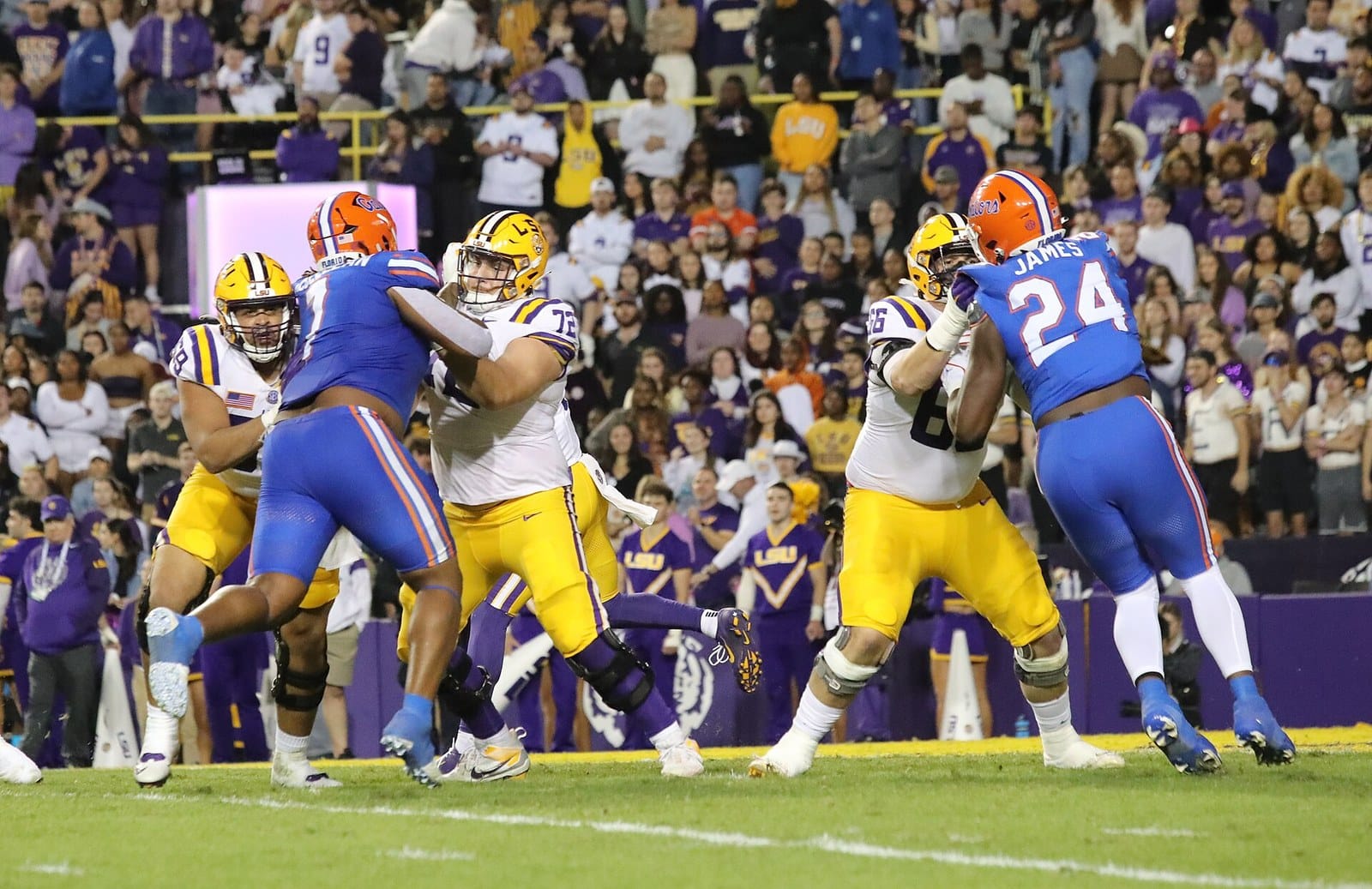 Florida players in royal blue road jerseys and orange helmets blocking against LSU in white at Tiger Stadium
