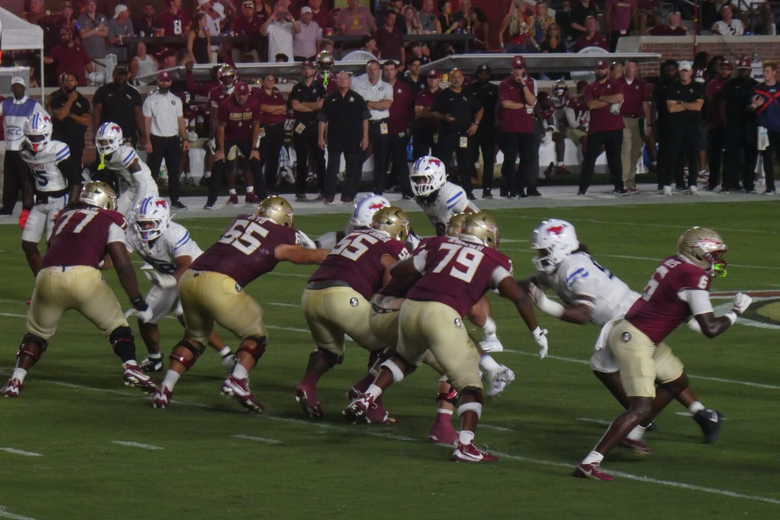 Florida State's offensive line in garnet jerseys and gold helmets blocks SMU at night at Doak Campbell Stadium