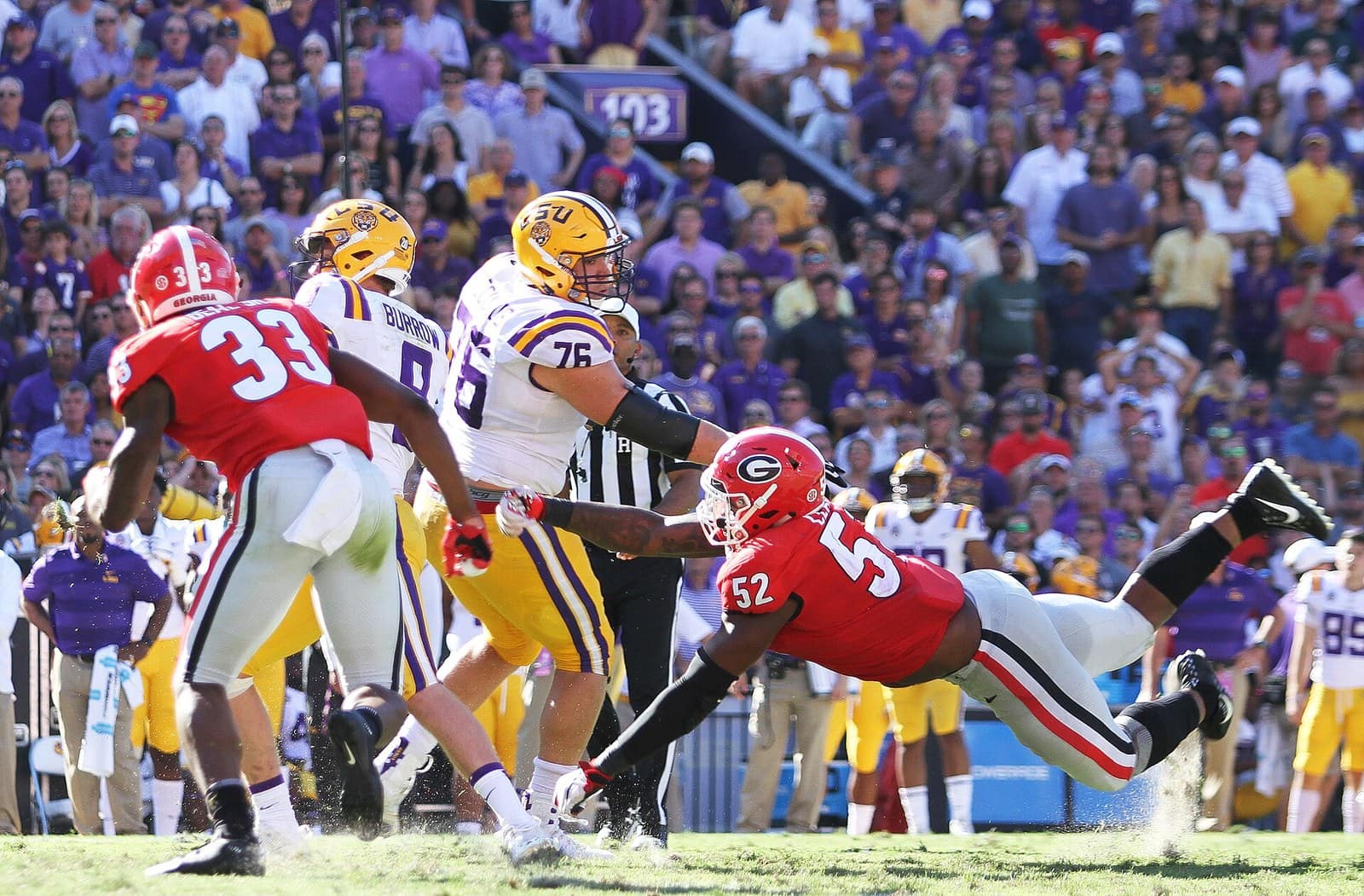 Georgia defenders in red jerseys, red helmets and silver pants rushing the LSU quarterback at Tiger Stadium