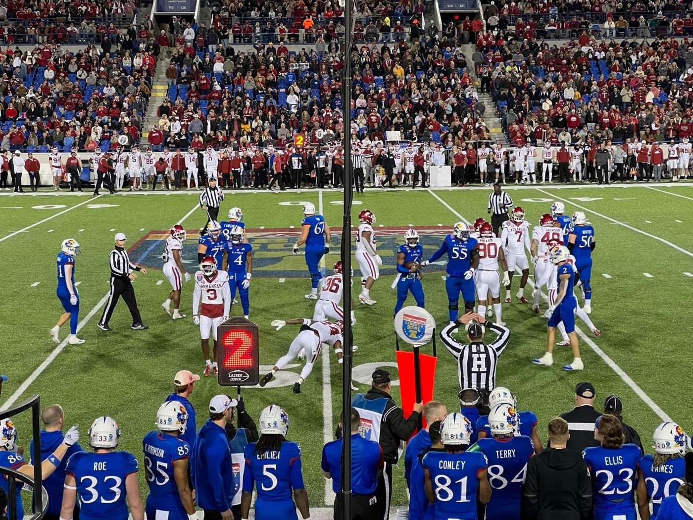 Kansas players in blue jerseys and white helmets on the field and sideline at the 2022 Liberty Bowl