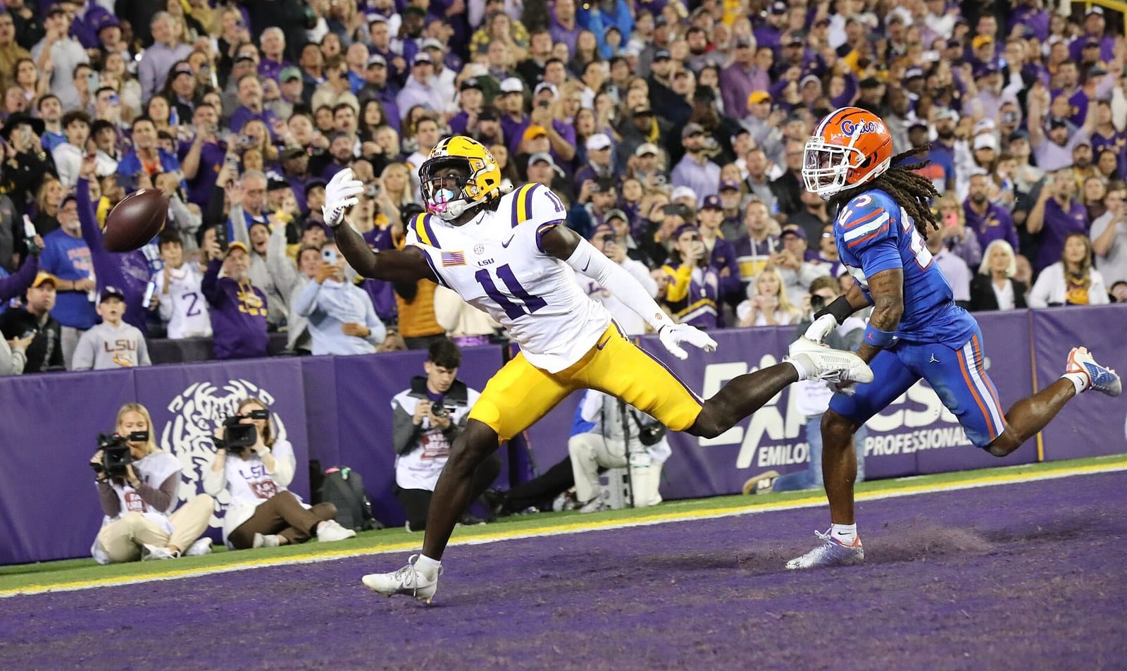 An LSU receiver in the white home jersey and gold helmet makes a catch in the end zone against Florida at Tiger Stadium