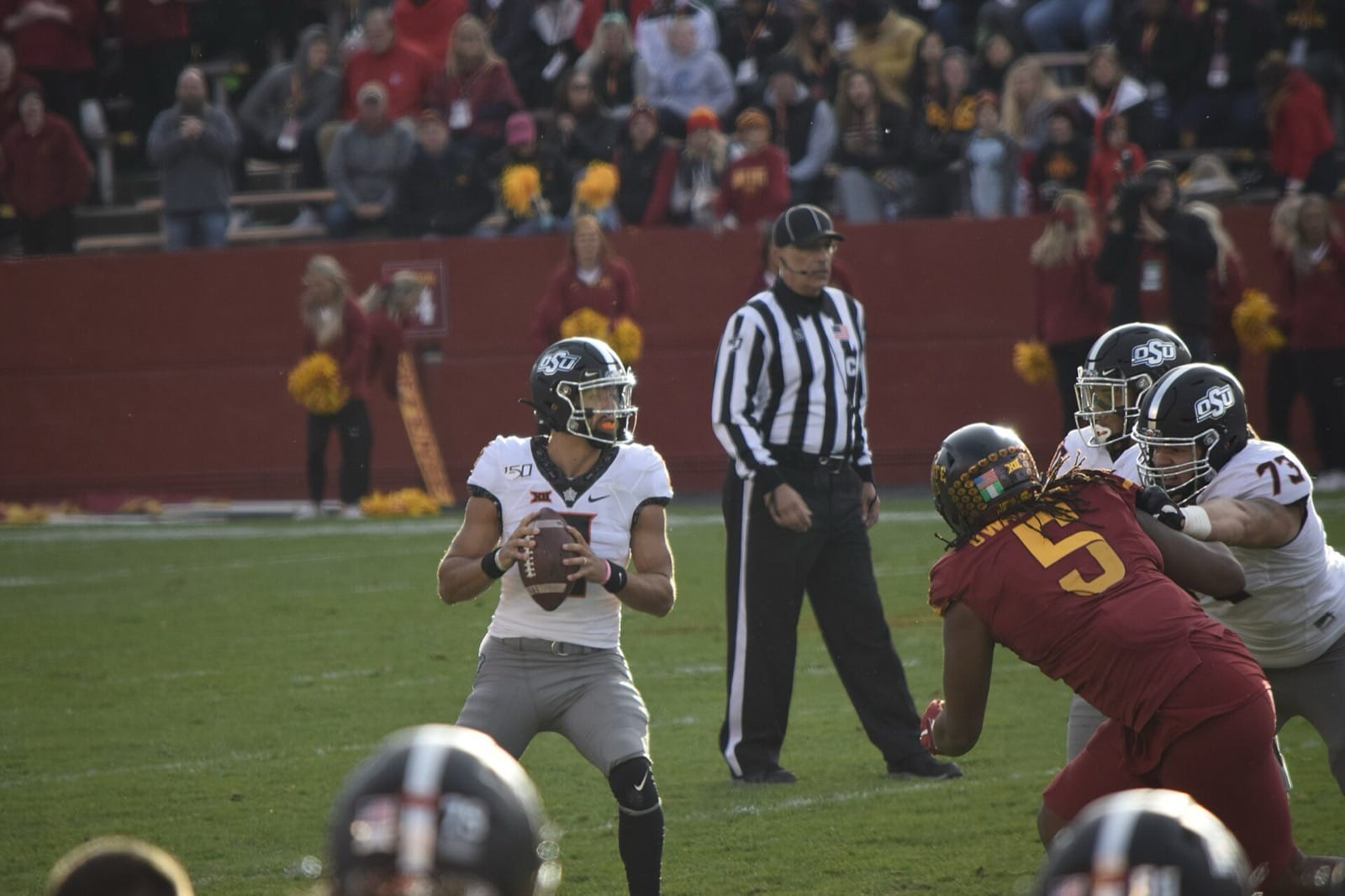 Oklahoma State quarterback Spencer Sanders sets to pass in a white jersey and black OSU helmet at Iowa State
