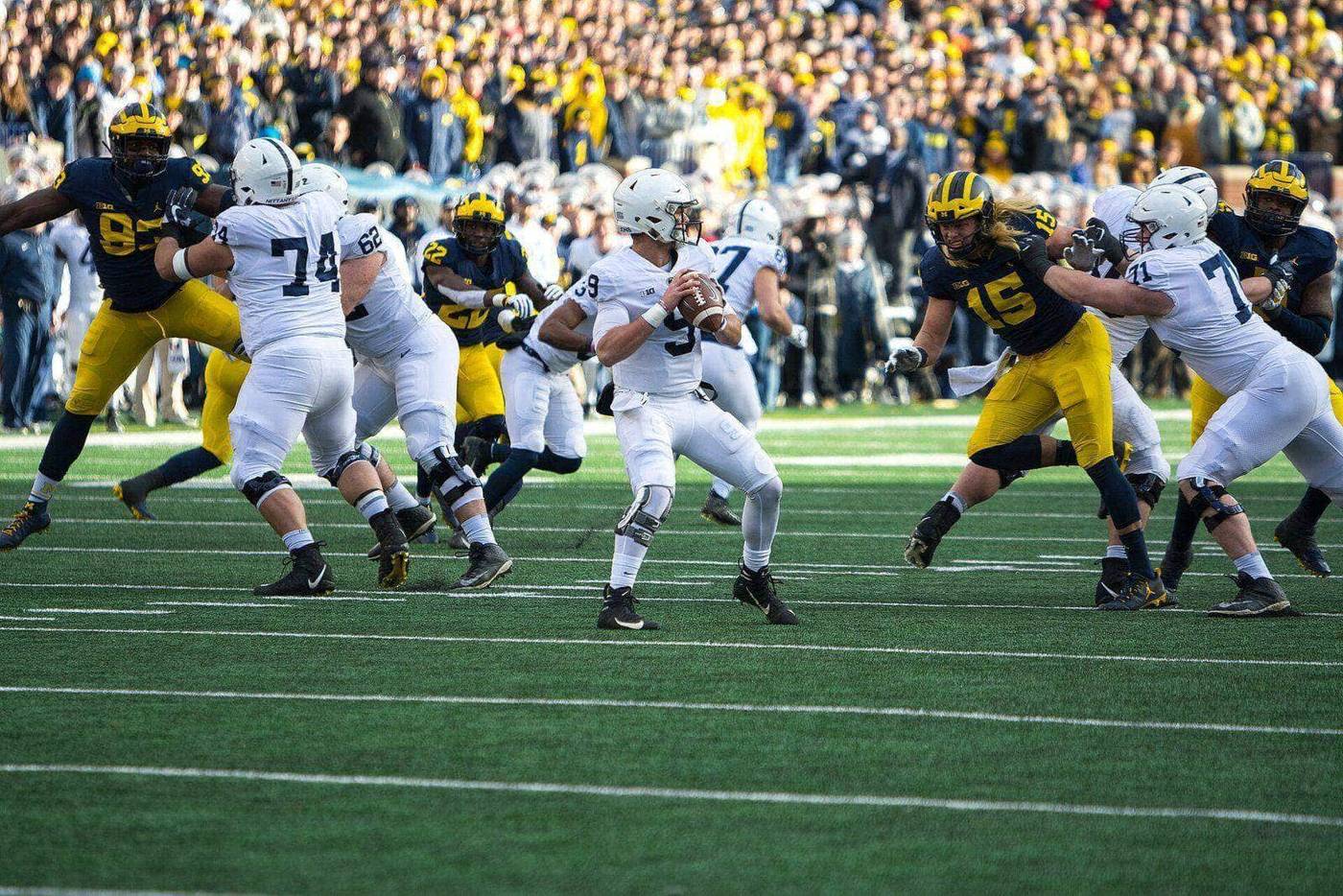 Penn State's offense in white road jerseys, white pants and white helmets blocking Michigan's defense at Michigan Stadium