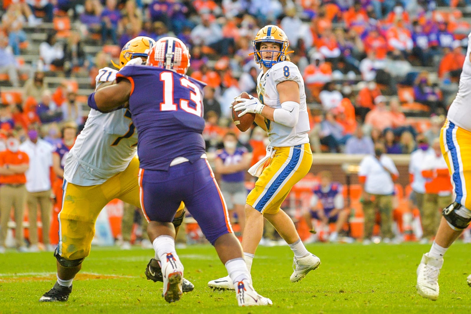 Pitt quarterback Kenny Pickett drops back in a white road jersey, gold pants and gold helmet at Clemson
