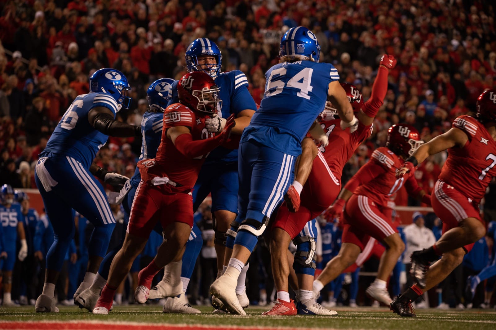 Utah players in red jerseys, red pants and red helmets at the line against BYU at Rice-Eccles Stadium