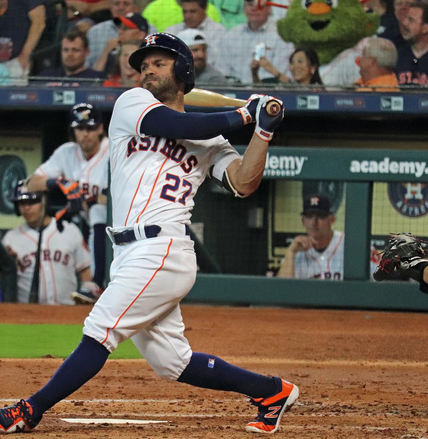 Jose Altuve swings in the Astros' white home jersey with navy and orange Astros lettering