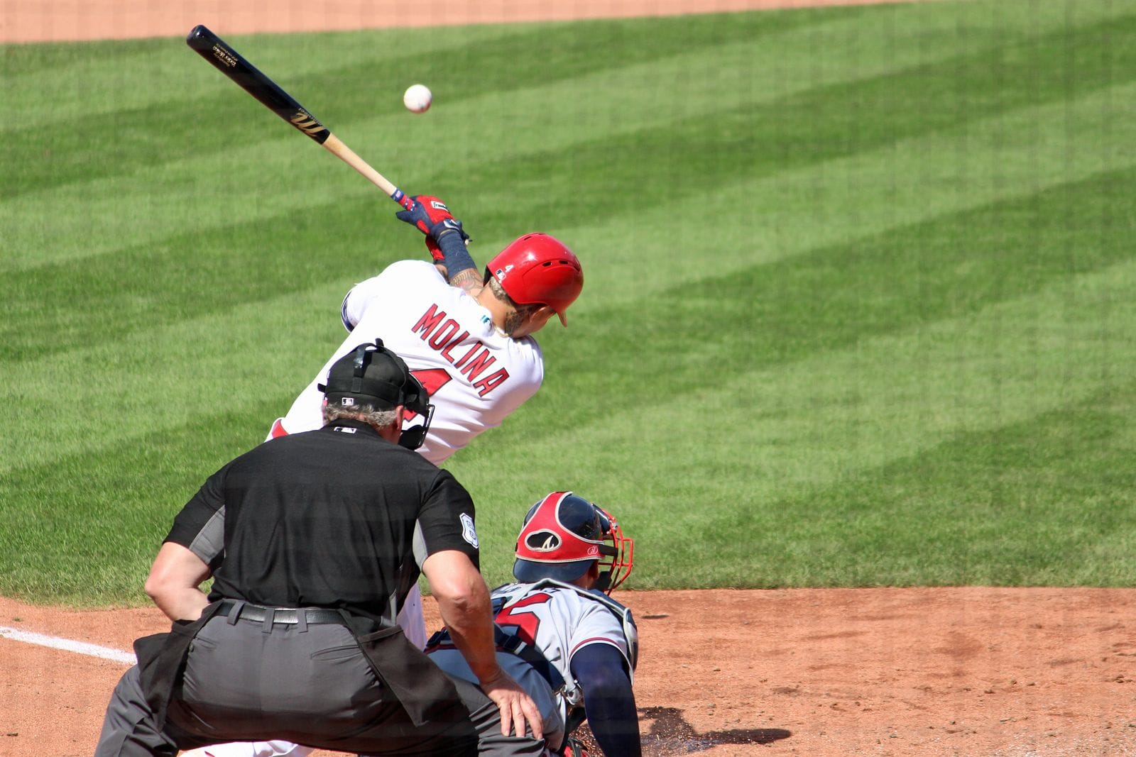 Yadier Molina swings in the Cardinals' home white uniform and red helmet