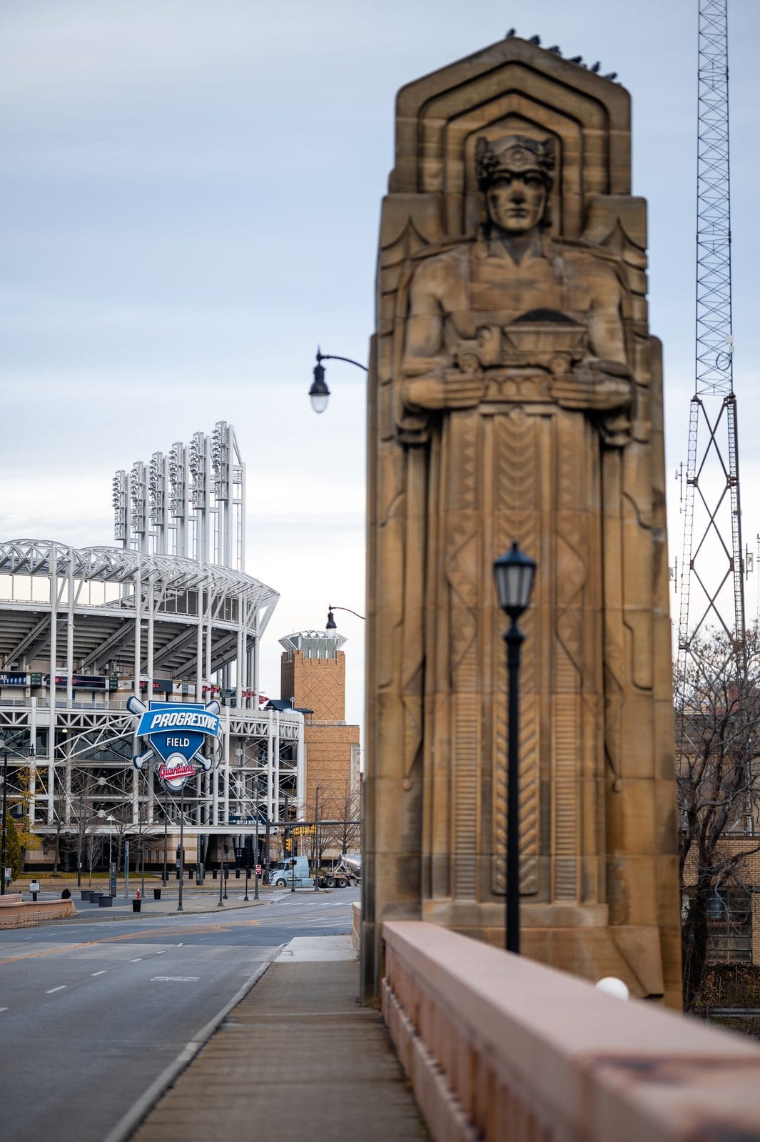 A Guardians of Traffic statue on Cleveland's Hope Memorial Bridge, with the ballpark behind it