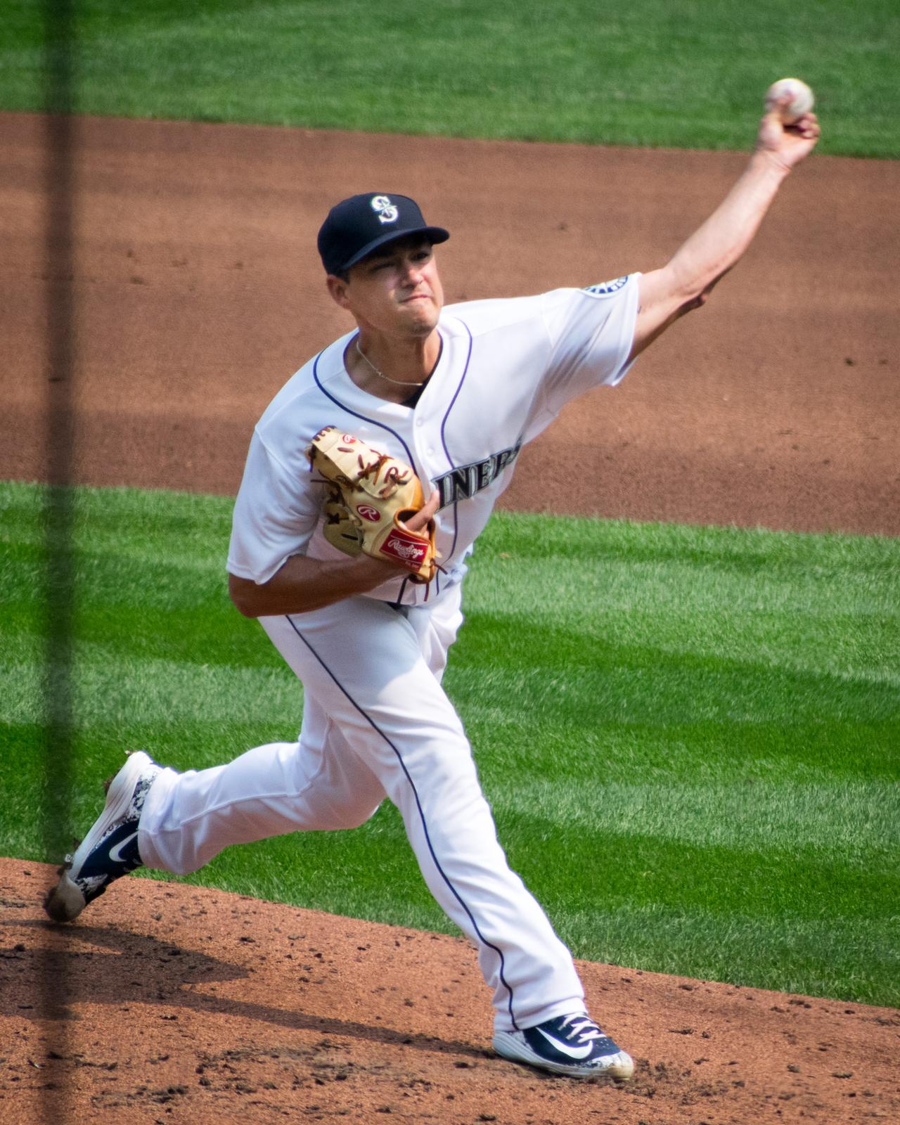 Marco Gonzales throws a pitch in the Mariners' white home uniform with a navy S cap