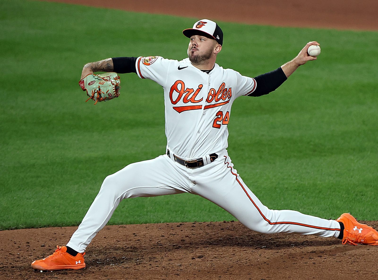 DL Hall delivers a pitch in the Orioles' white home uniform with orange Orioles script
