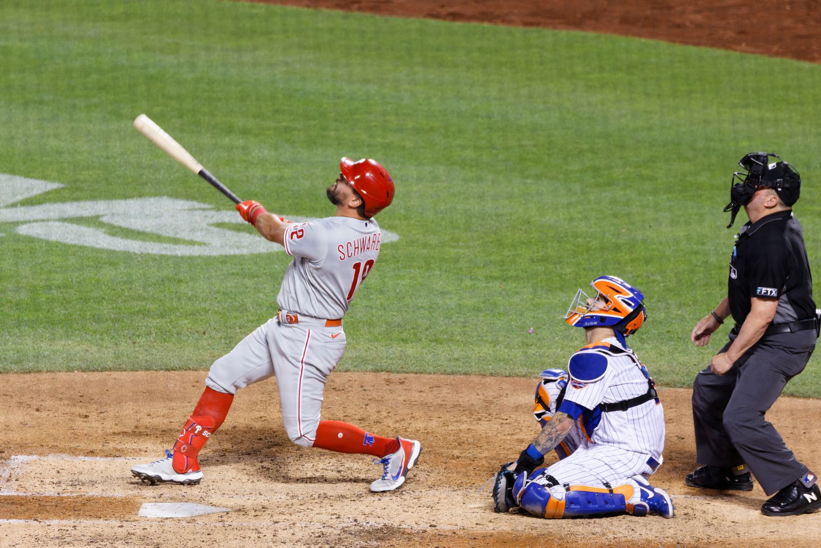Kyle Schwarber watches a fly ball in the Phillies' road gray uniform and red helmet