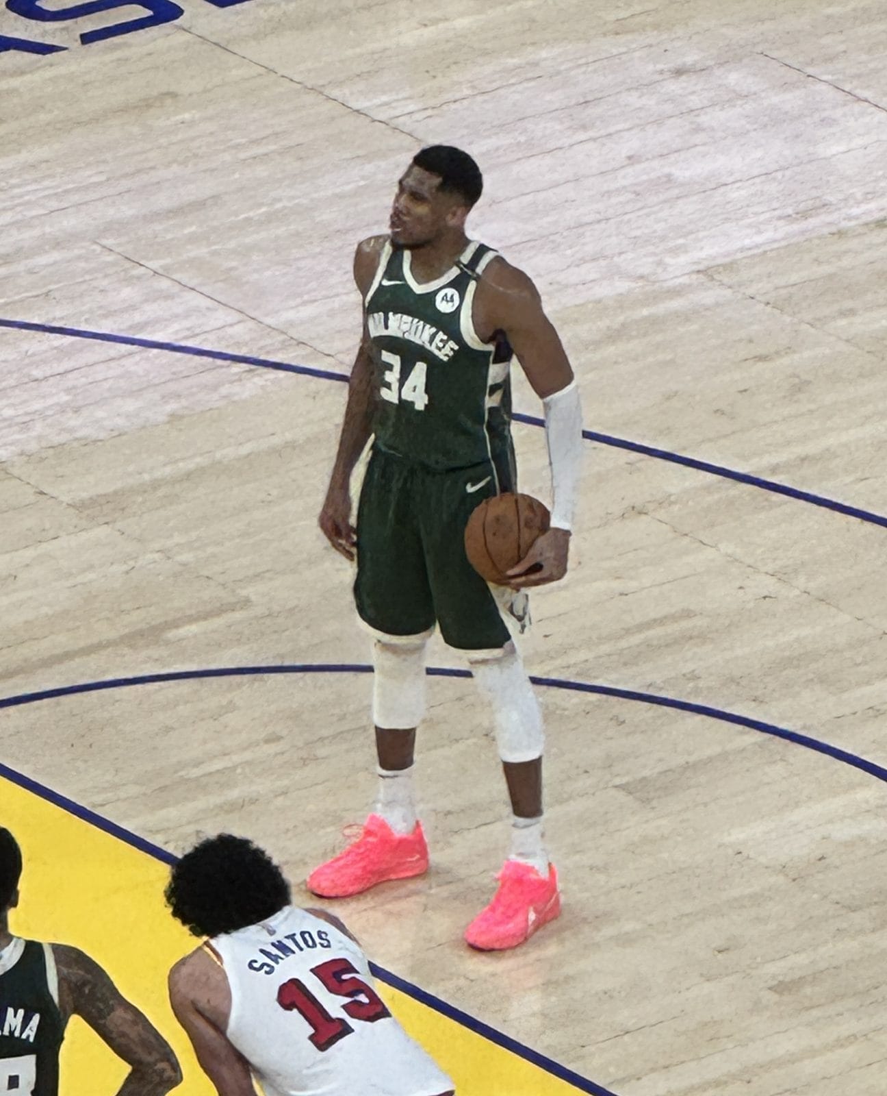 Giannis Antetokounmpo waits at the free-throw line in the Bucks' green road uniform, MILWAUKEE over No. 34, at Chase Center in San Francisco, March 18, 2025; Warriors players in white in the foreground