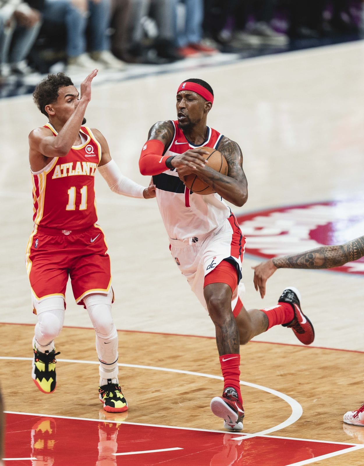 Trae Young drives in the Hawks' red road uniform, ATLANTA across the chest and No. 11, against a Wizards defender in white at Capital One Arena, October 2021