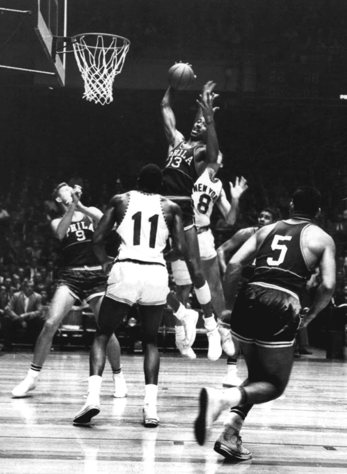 Wilt Chamberlain of the Philadelphia Warriors, PHILA on his dark jersey, goes up for a rebound against the New York Knicks in 1960