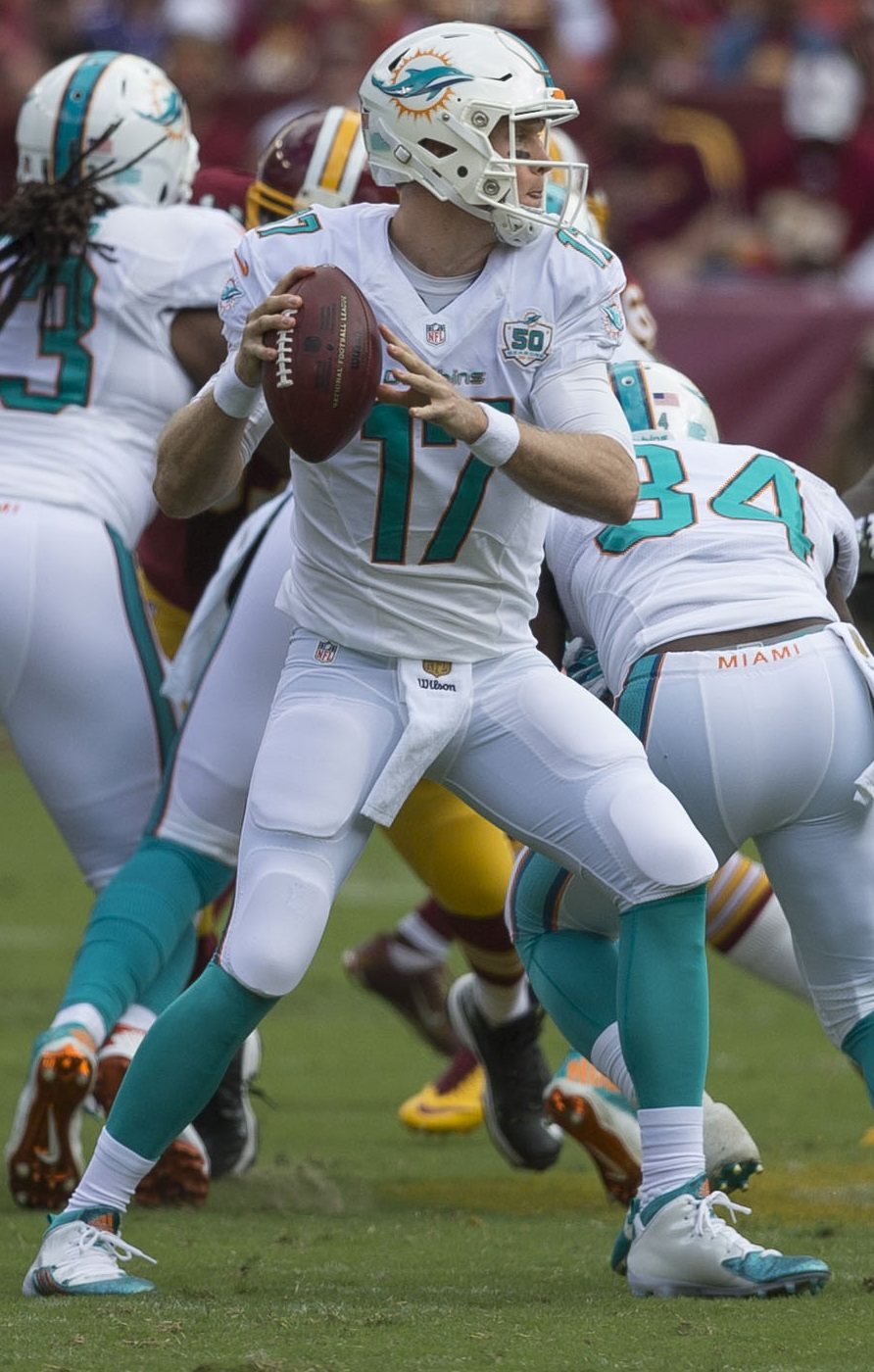 Dolphins quarterback Ryan Tannehill drops back in the white road jersey with aqua numbers, aqua pants and the white helmet with the 2013 dolphin logo, wearing the team's 50th-season patch, against Washington at FedExField on Sept. 13, 2015