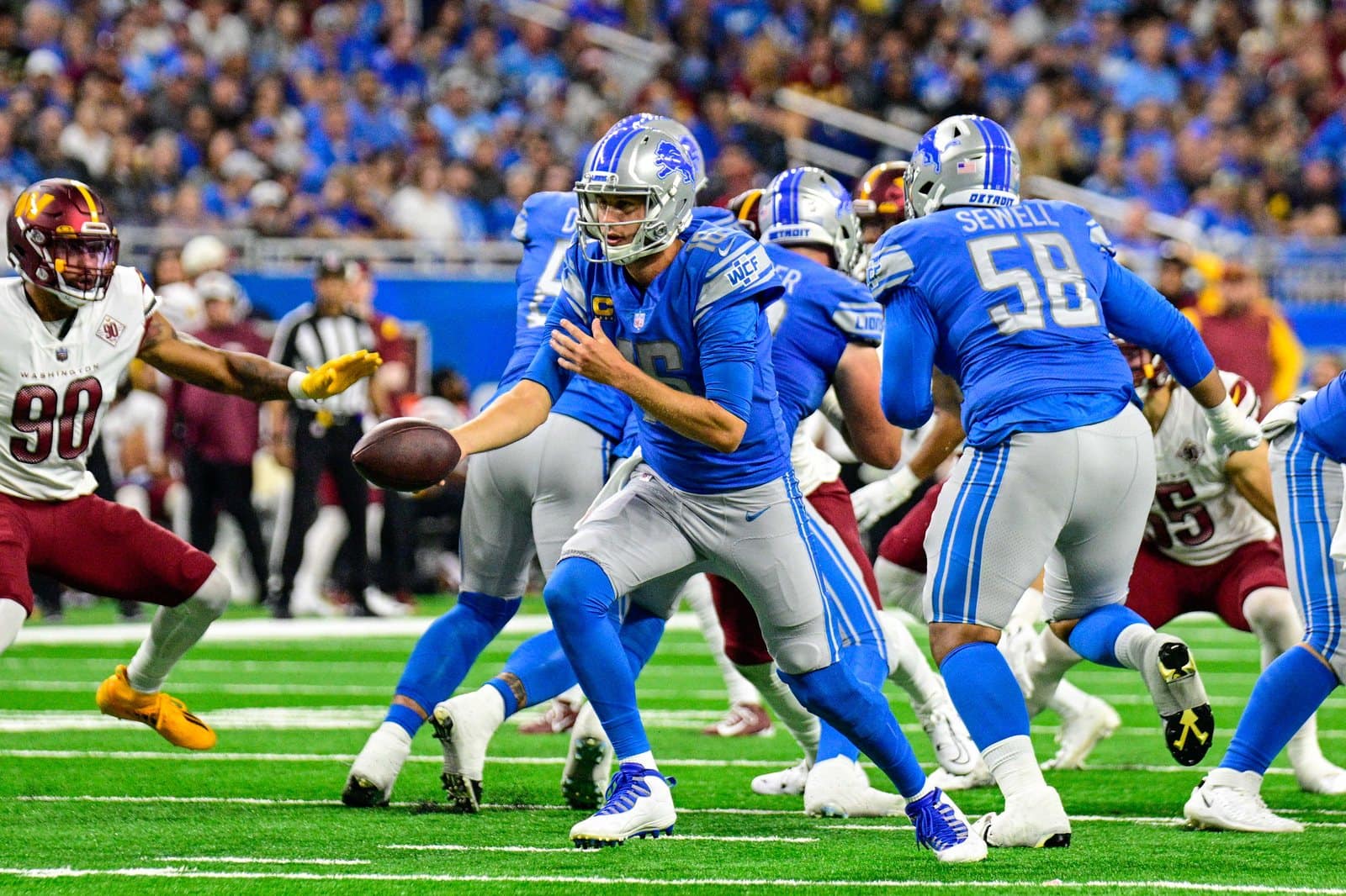 Lions quarterback Jared Goff hands off in the Honolulu Blue home jersey, silver pants and silver helmet against the Commanders at Ford Field in Detroit on Sept. 18, 2022