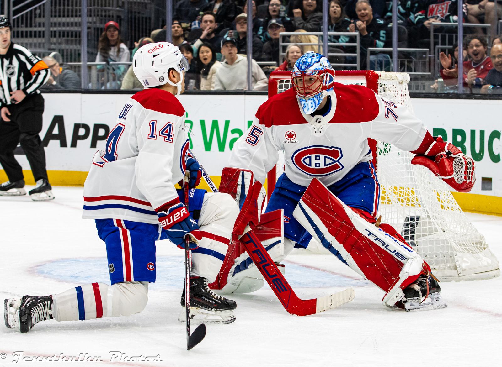 Captain Nick Suzuki, No. 14, in the Canadiens' white road uniform with the CH crest and red and blue stripes, beside goalie Jakub Dobes at Climate Pledge Arena in Seattle, March 12, 2025