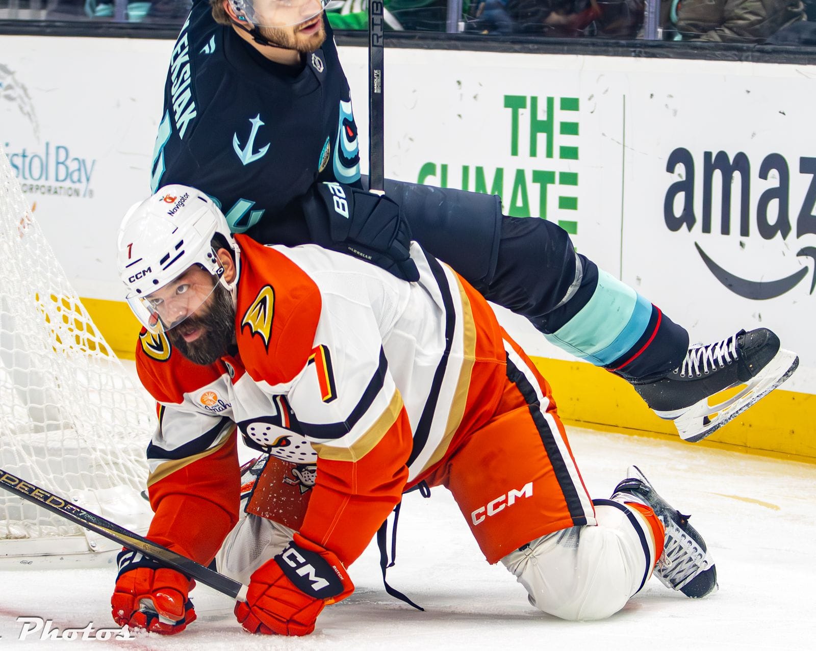 Radko Gudas in the Ducks' white road uniform with orange shoulders and the webbed-foot D crest, No. 7, tangled with the Kraken's Jamie Oleksiak at Climate Pledge Arena in Seattle, January 28, 2025