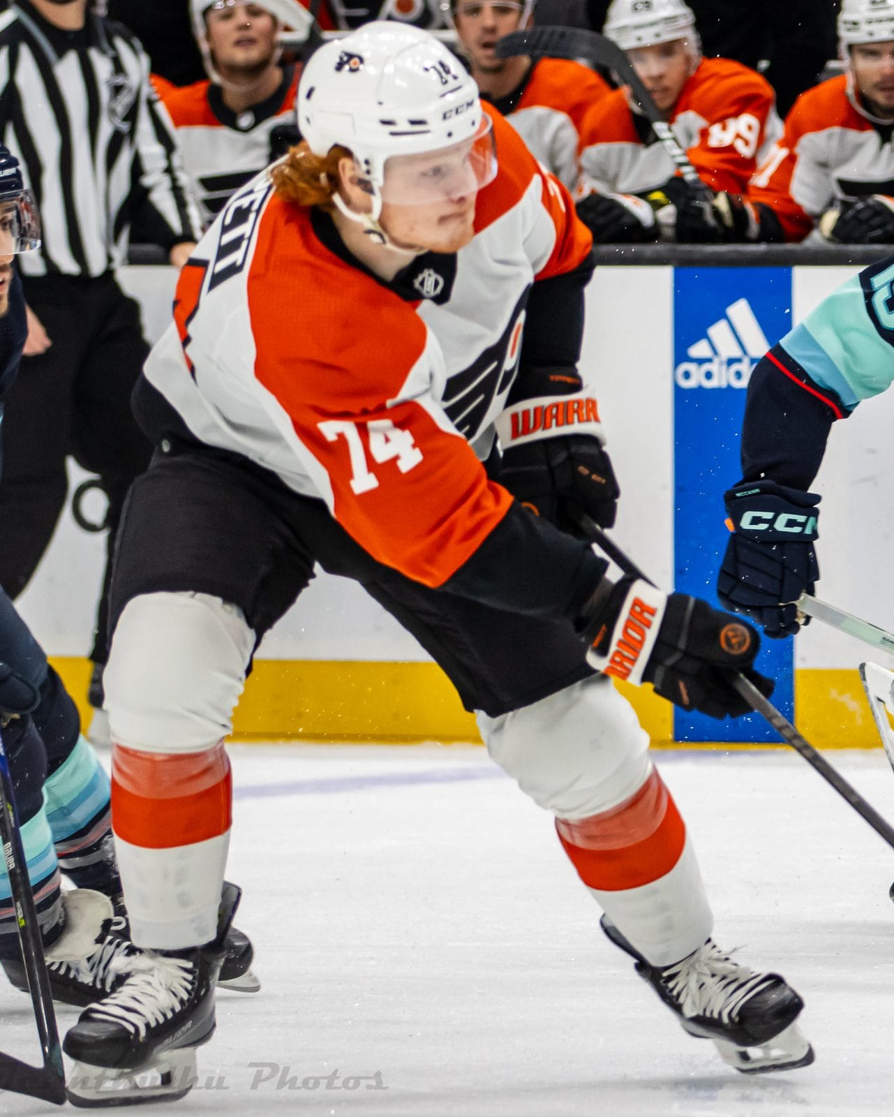 Owen Tippett in the Flyers' white road uniform with orange shoulders and the winged-P crest, No. 74, skates past the Kraken's Jared McCann at Climate Pledge Arena in Seattle, December 29, 2023