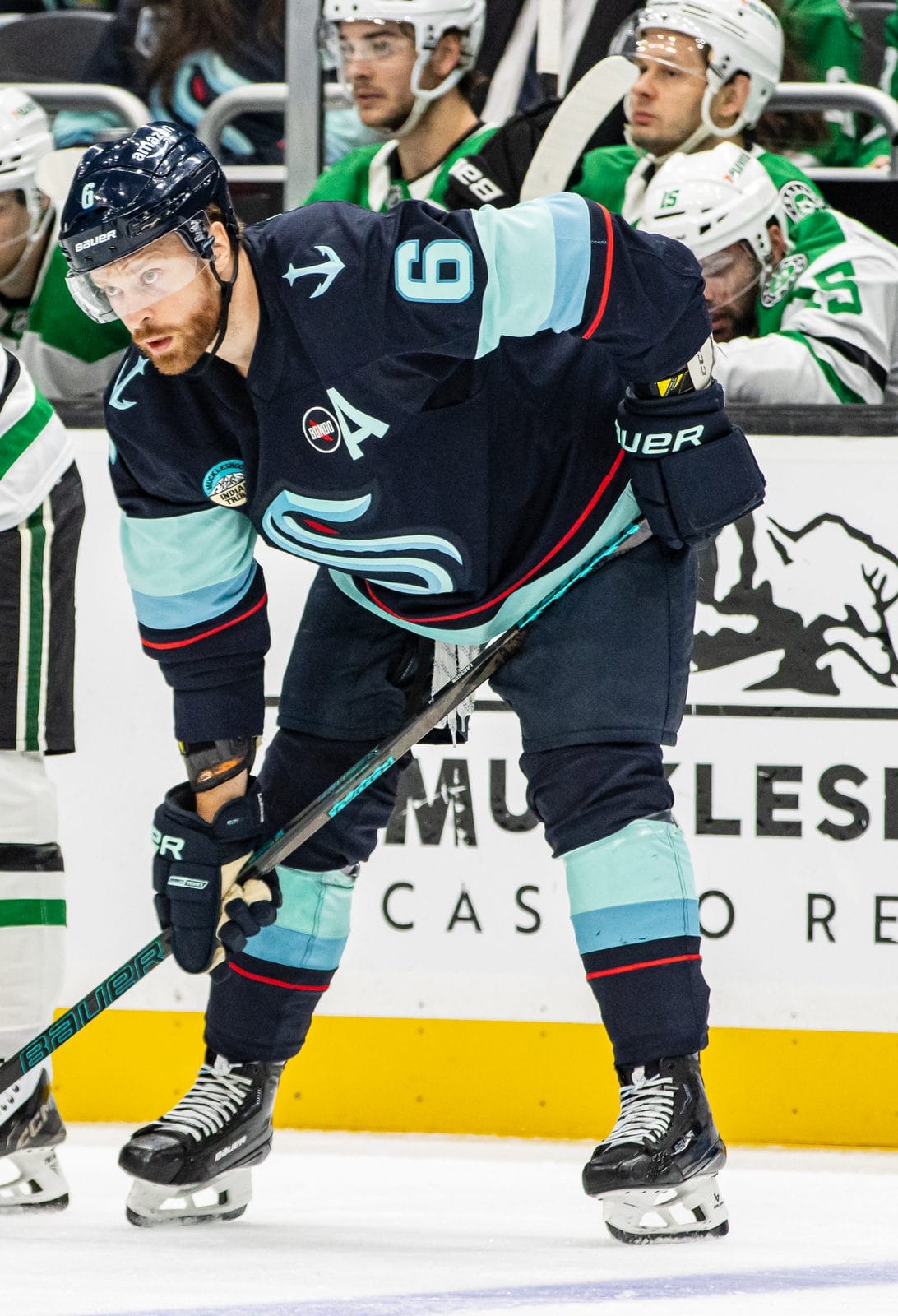 Adam Larsson, wearing an A, in the Kraken's deep sea blue home uniform with the S crest, No. 6, lines up for a faceoff against the Stars' Matt Duchene at Climate Pledge Arena in Seattle, March 31, 2025