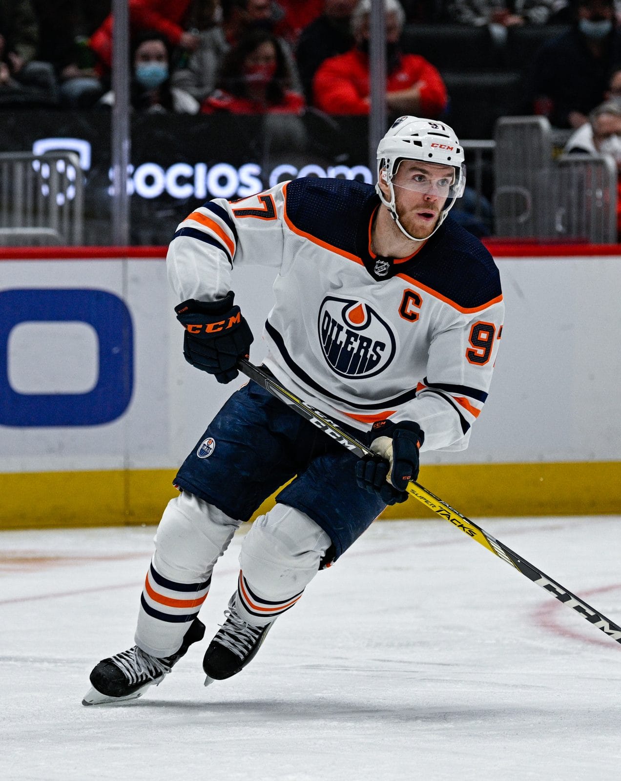 Captain Connor McDavid carries the puck in the Oilers' white road uniform with orange and navy trim and the oil-drop crest, No. 97, at Capital One Arena in Washington, February 2, 2022