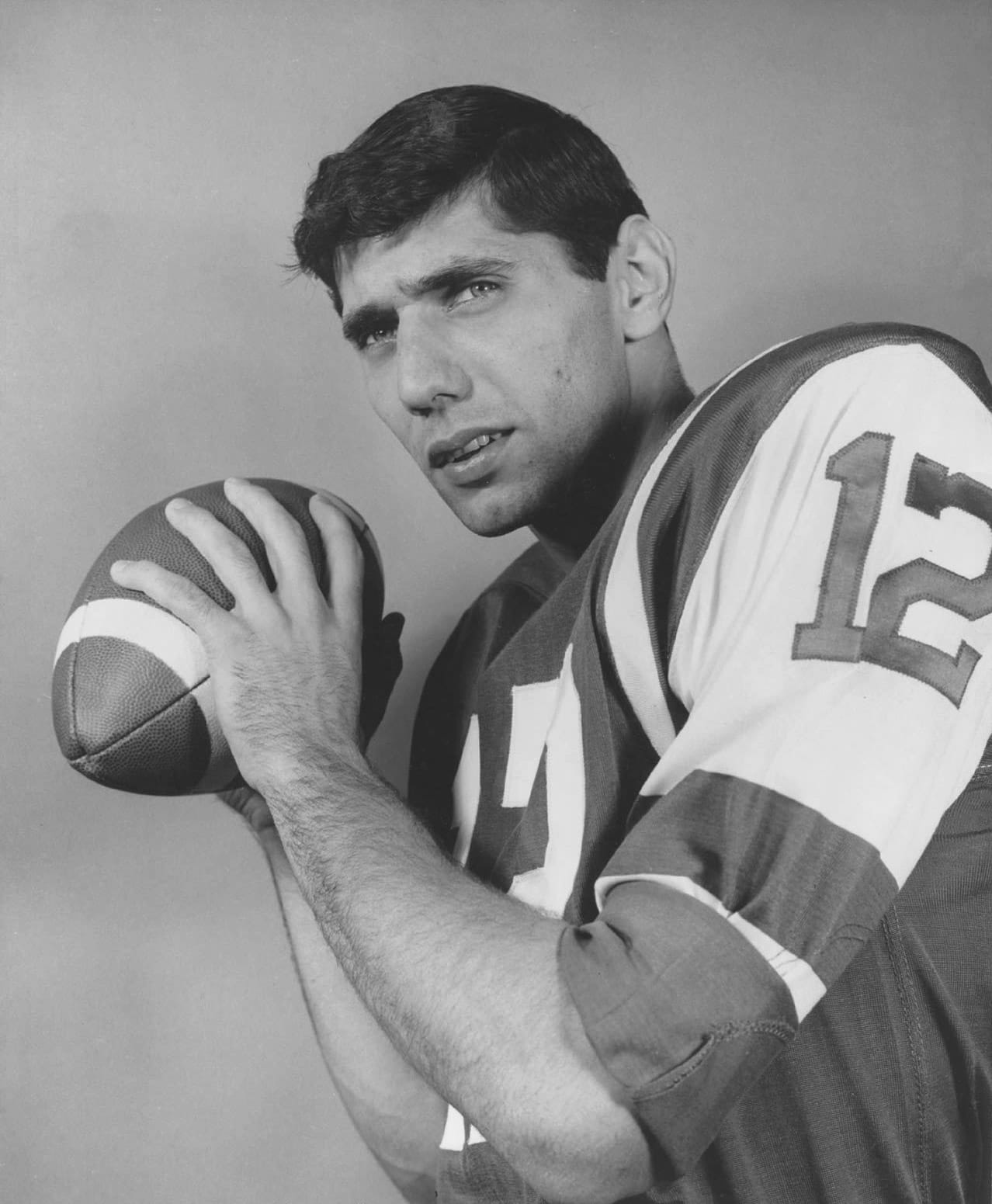 Joe Namath in a Jets jersey with number 12 and striped sleeves, holding a football, 1965