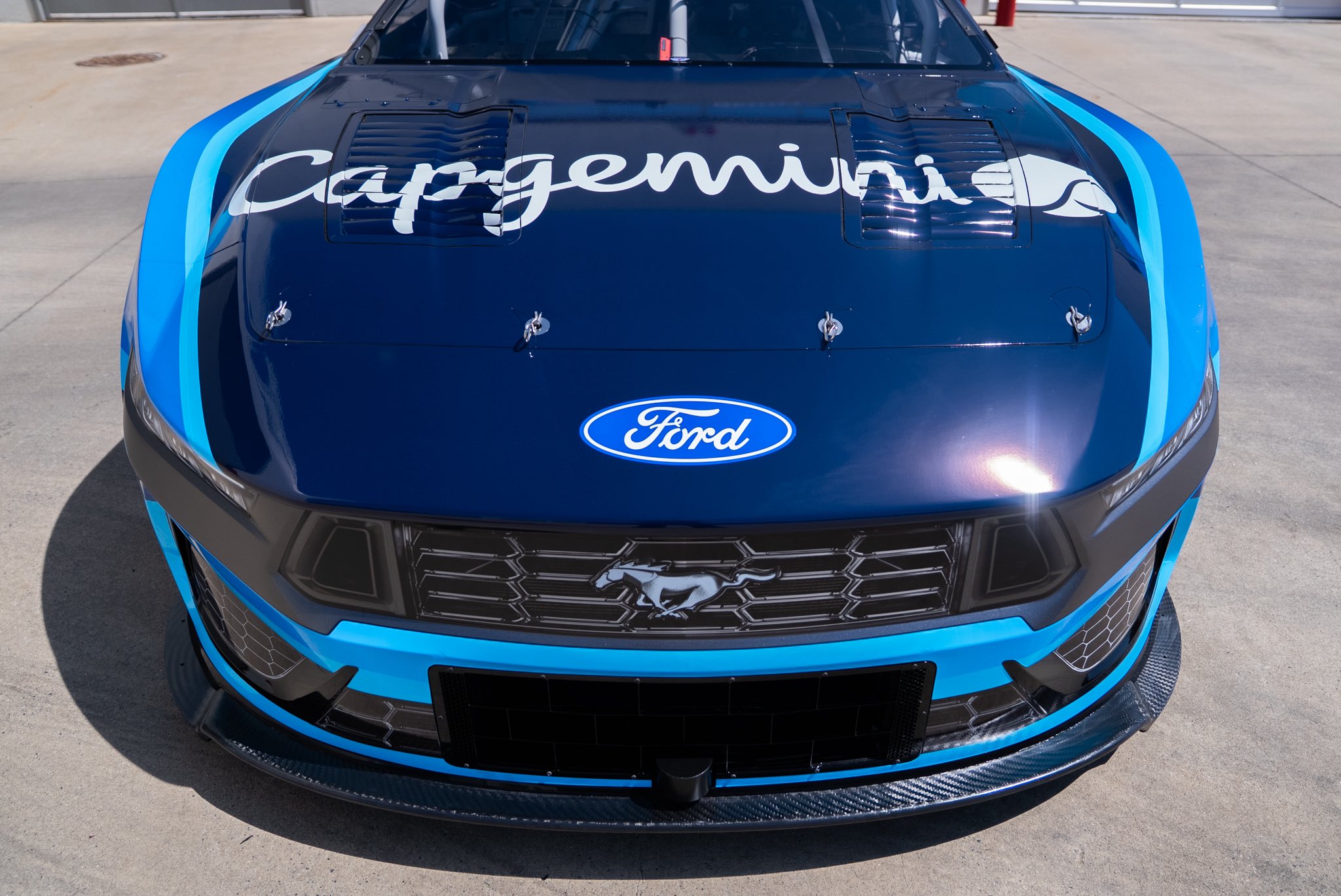Front view of Josh Berry's #21 Wood Brothers Racing Ford Mustang Dark Horse for the 2026 NASCAR Cup Series with the Capgemini script wordmark across the hood above the Ford oval and the Mustang grille emblem at the front
