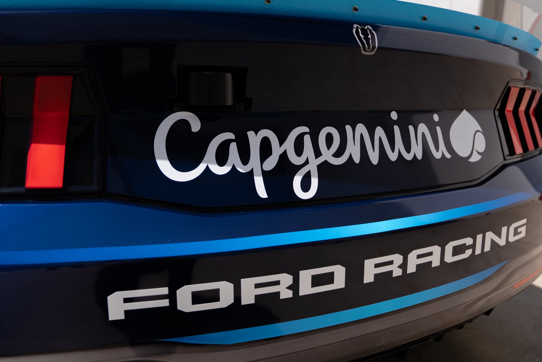 Close-up of the Capgemini script wordmark on the rear decklid of Josh Berry's #21 Wood Brothers Racing Ford Mustang Dark Horse for the 2026 NASCAR Cup Series with the FORD RACING wordmark below