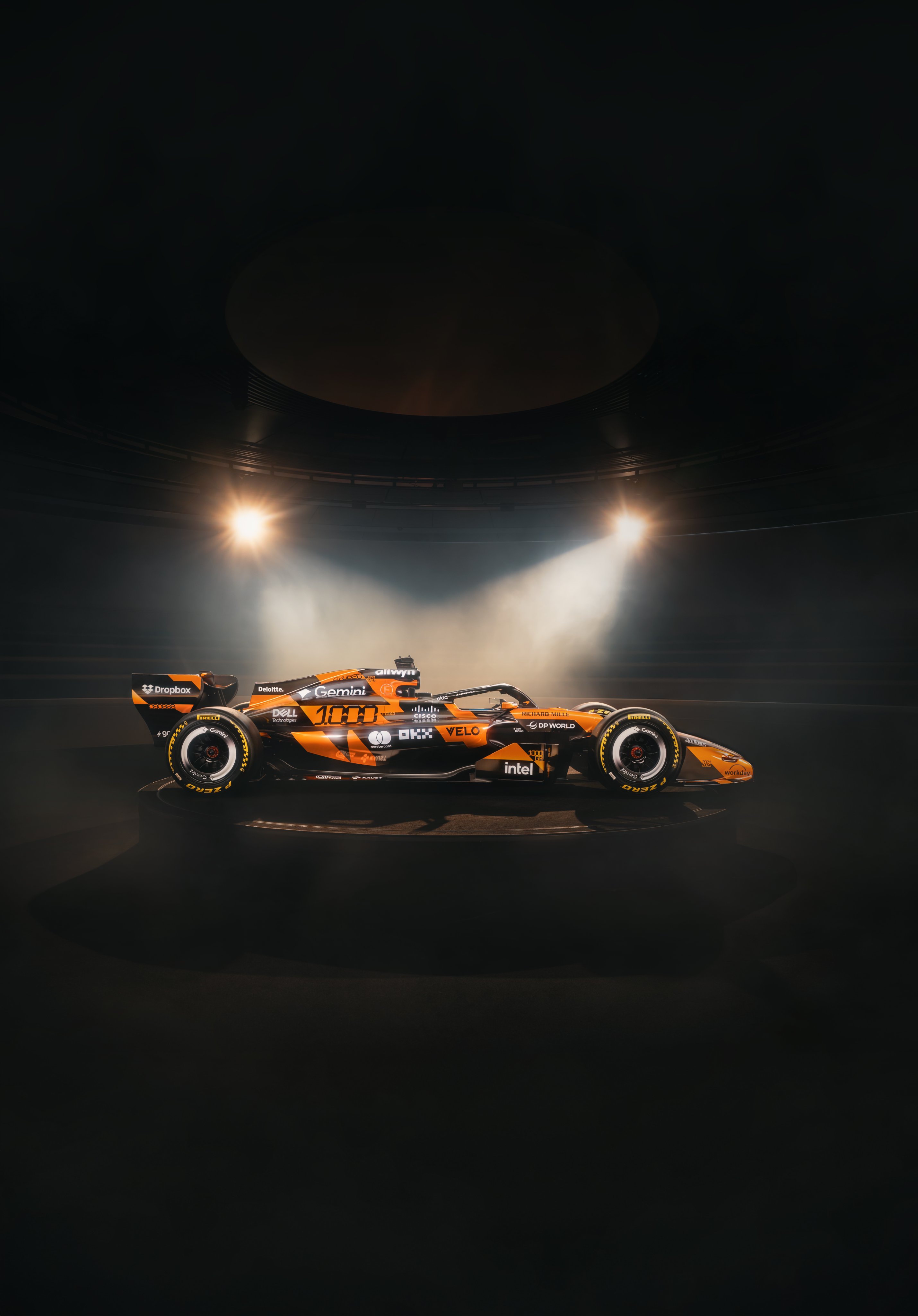 McLaren F1 Monaco Grand Prix 2026 special livery showing the engine cover and airbox detail with the orange and black retro treatment in front of the fragmented McLaren typography wall installation