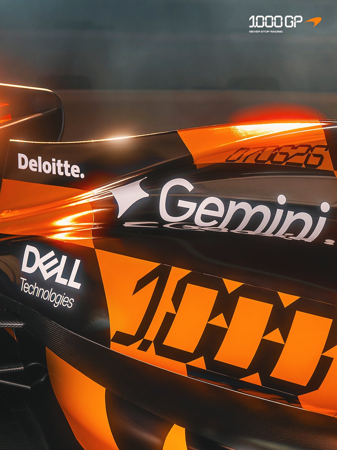 McLaren F1 Monaco Grand Prix 2026 special livery side view of the MCL40 in the orange and black retro paint set against the deep studio backdrop with the 1000th GP typography wall behind the car