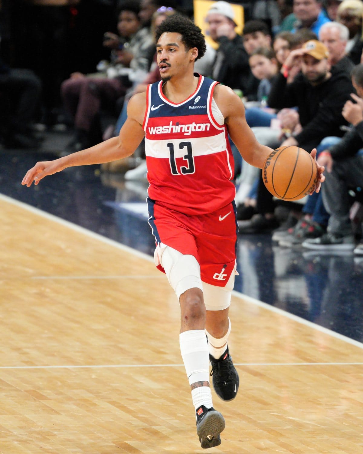 Wizards guard Jordan Poole dribbles up the court in Washington's red Icon Edition jersey with the navy and white WASHINGTON chest stripe and red shorts in 2024