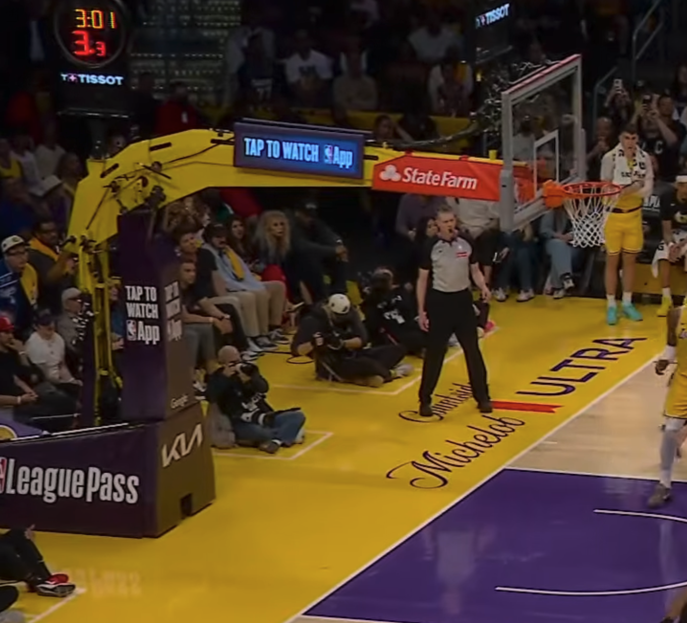 Crypto.com Arena 2026 NBA Playoffs Round 1 backboard with Tap To Watch NBA App and State Farm branding and no playoff logo on the stanchion, identical to a regular season home game setup and the second straight postseason without the Playoffs logo on the stanchion base