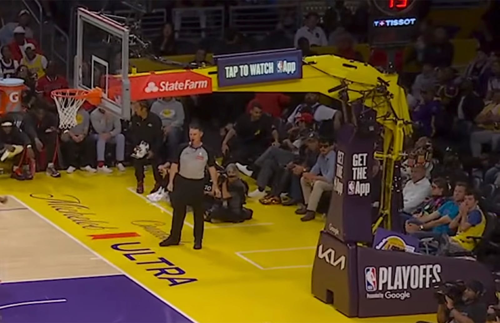 NBA Playoffs logo on the side of the stanchion at Crypto.com Arena during Lakers vs Rockets 2026 NBA Playoffs Round 1 Game 5 with a Get The App NBA App ad and Kia branding wrapped across the main camera-facing panel
